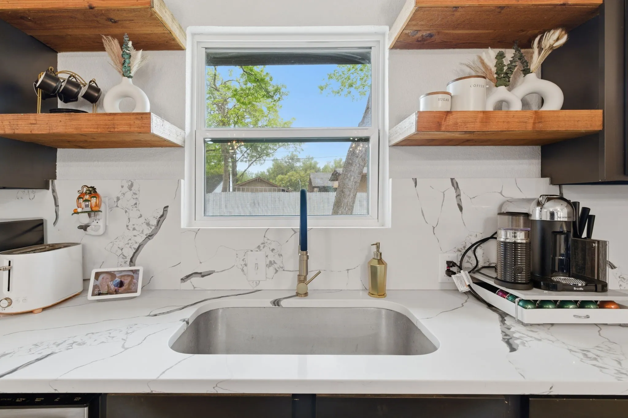 Kitchen with open shelves, tasteful backsplash, and light stone countertops