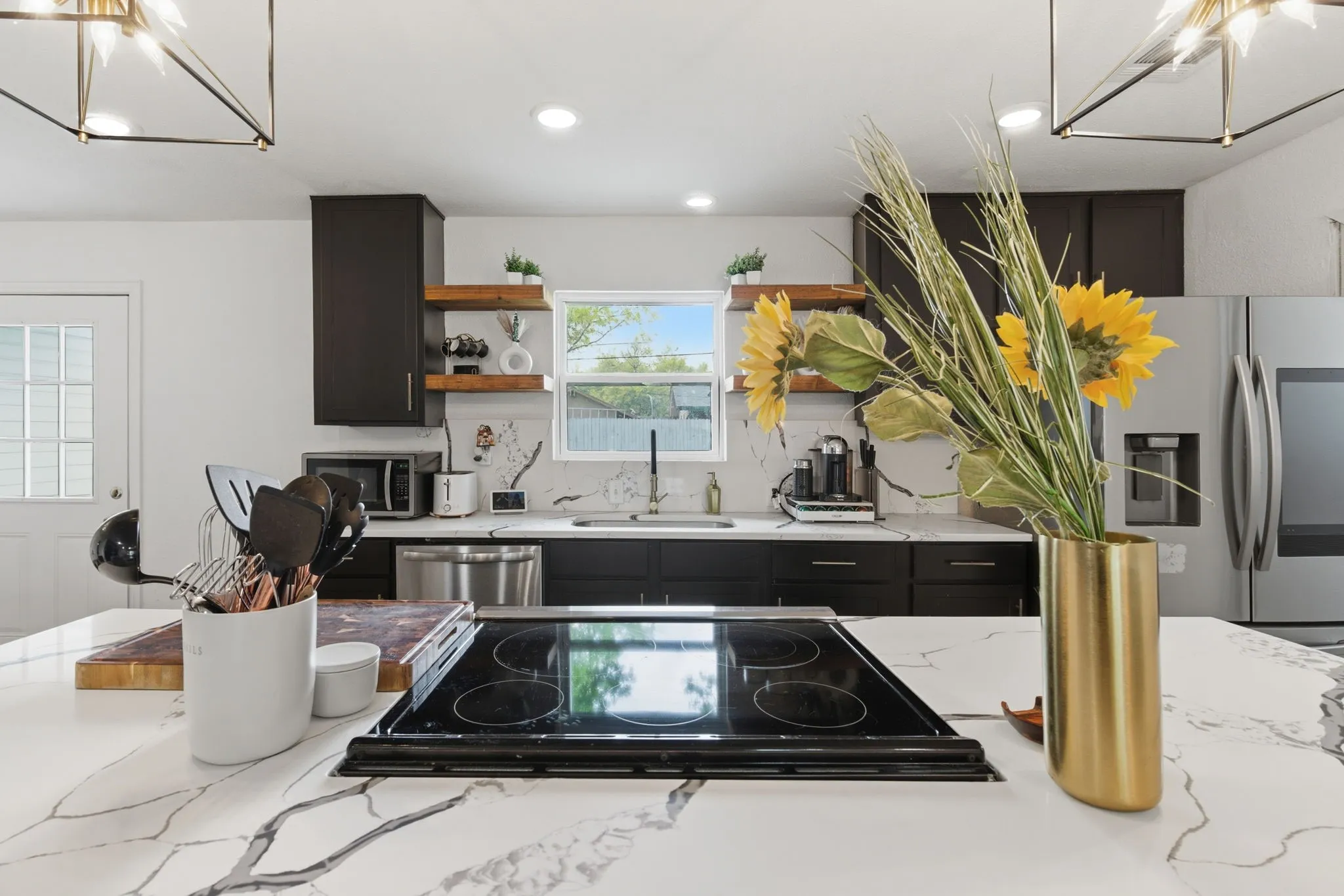 Kitchen featuring suspended lighting, light stone countertops, and backsplash