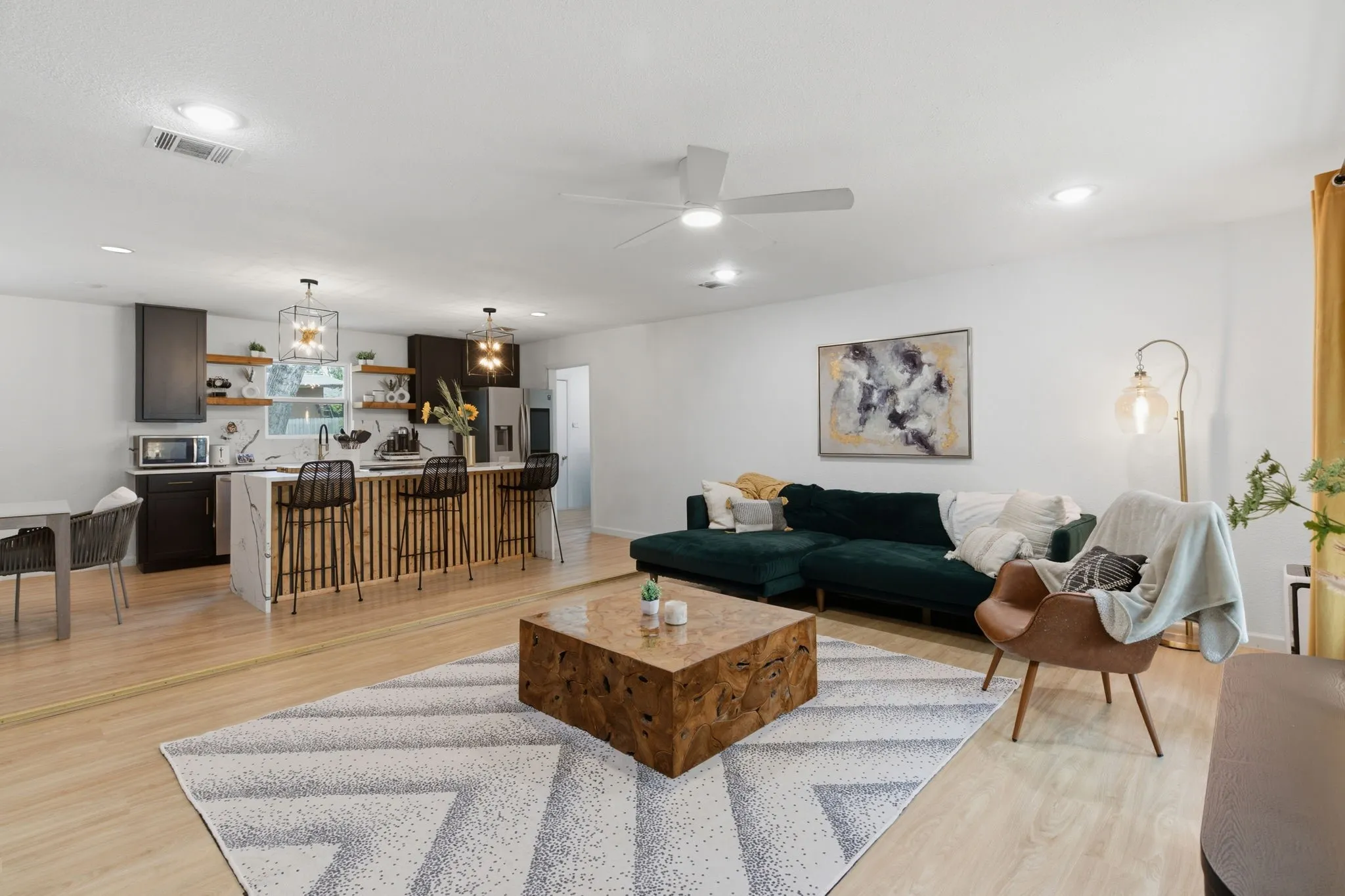 Living area with a ceiling fan, light wood finished floors, and hanging lights