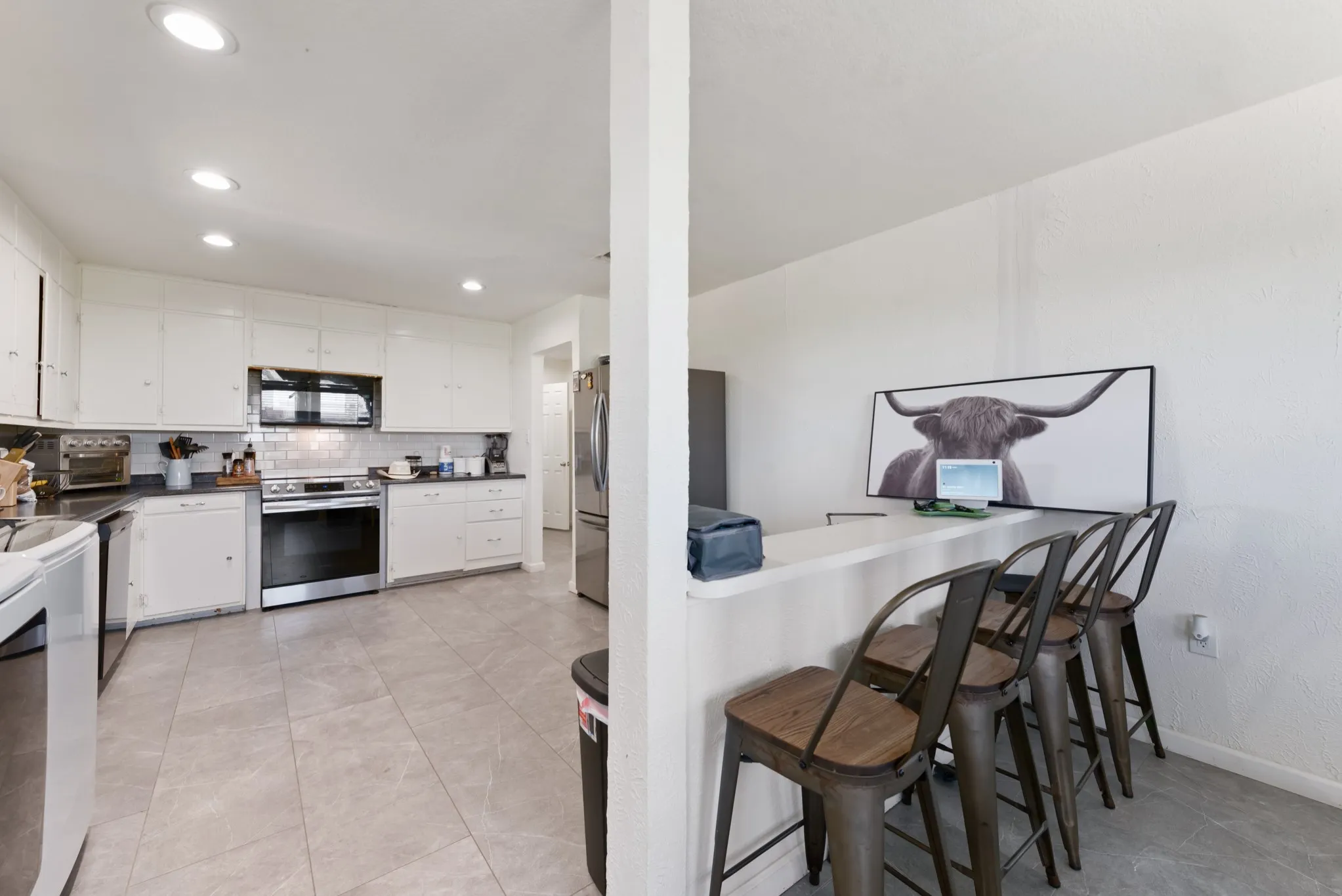Kitchen featuring white cabinetry, stainless steel appliances, dark countertops, a white subway tile backsplash, and recessed lighting