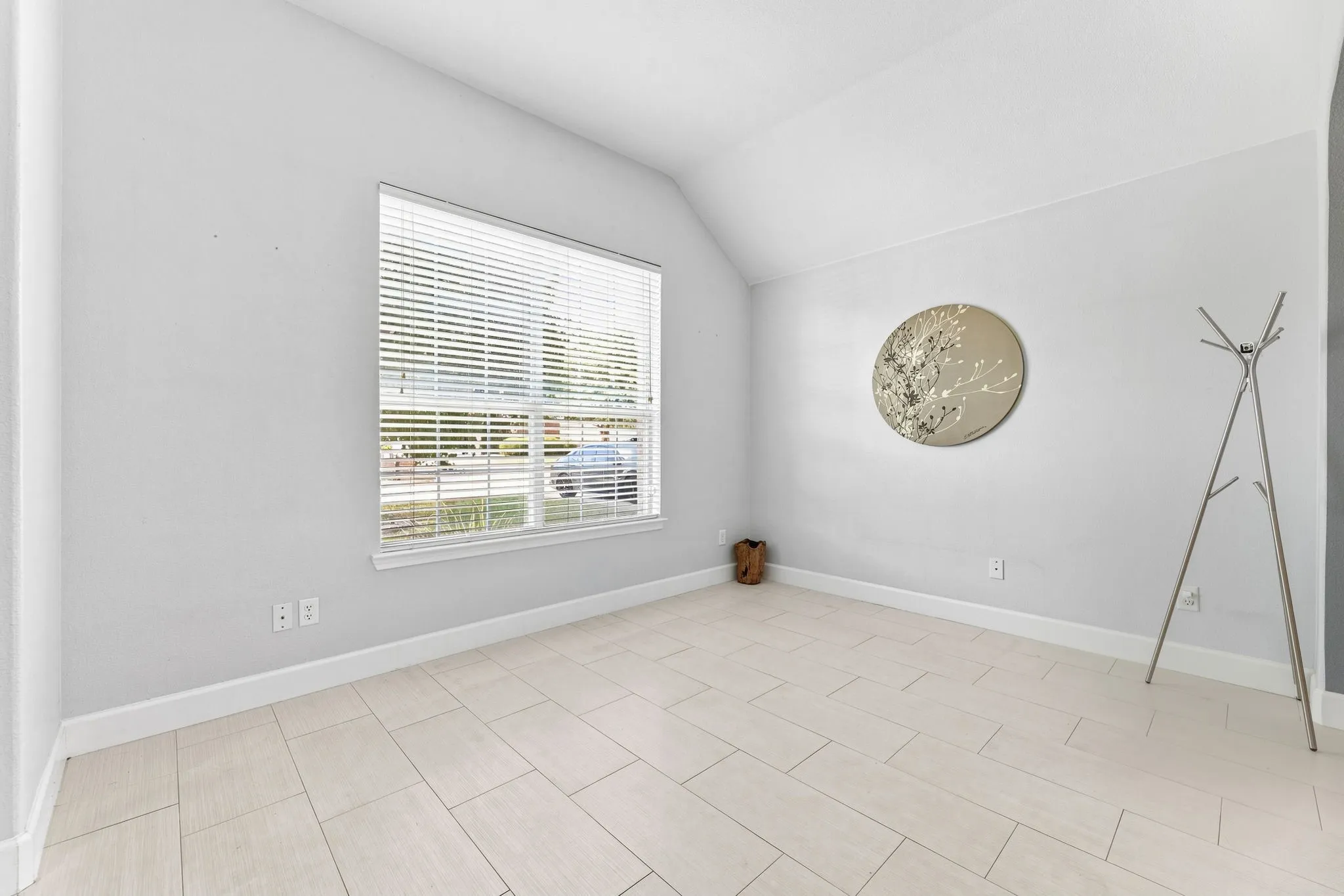 Vaulted ceiling, neutral wall paint, horizontal blinds, tile flooring, window