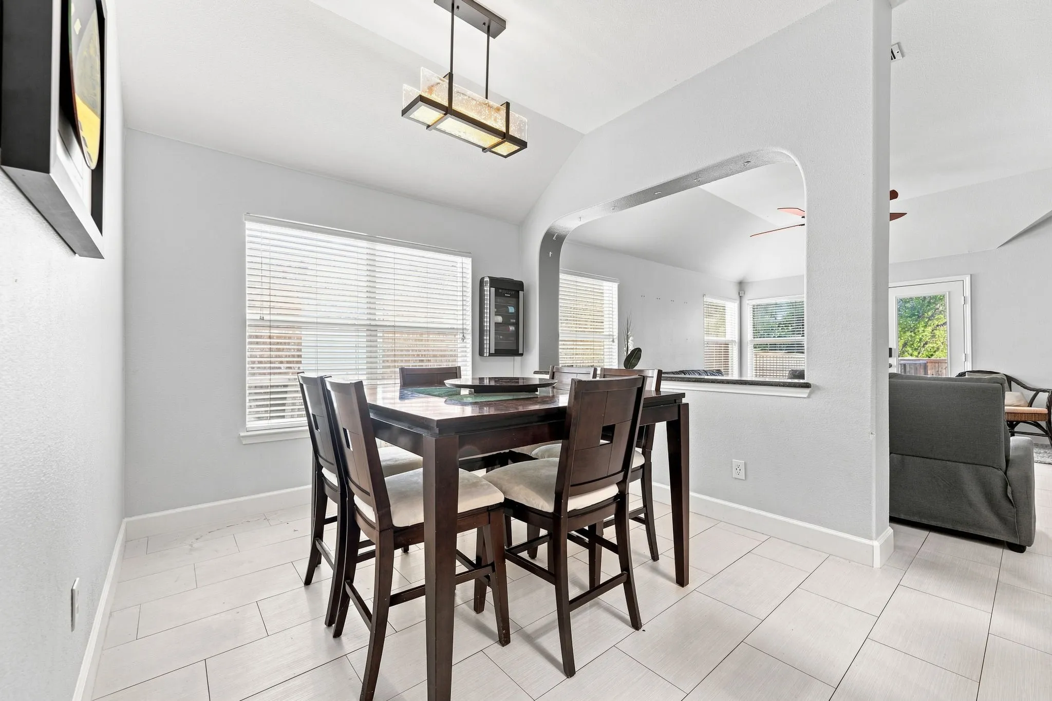 Dining area featuring light-toned tile flooring, a window with blinds, and a built-in wall niche