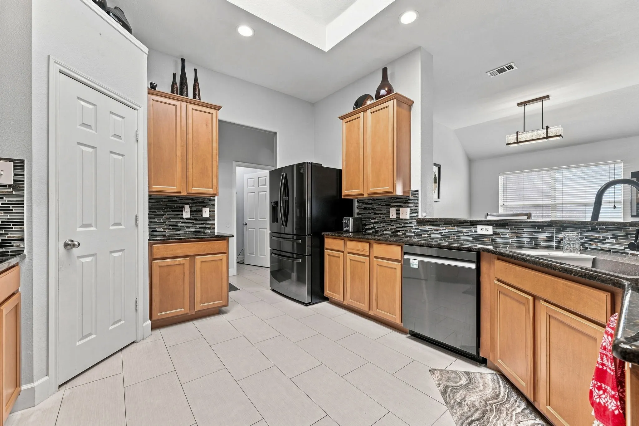 Kitchen featuring wood cabinetry, dark countertops, and a full tile backsplash