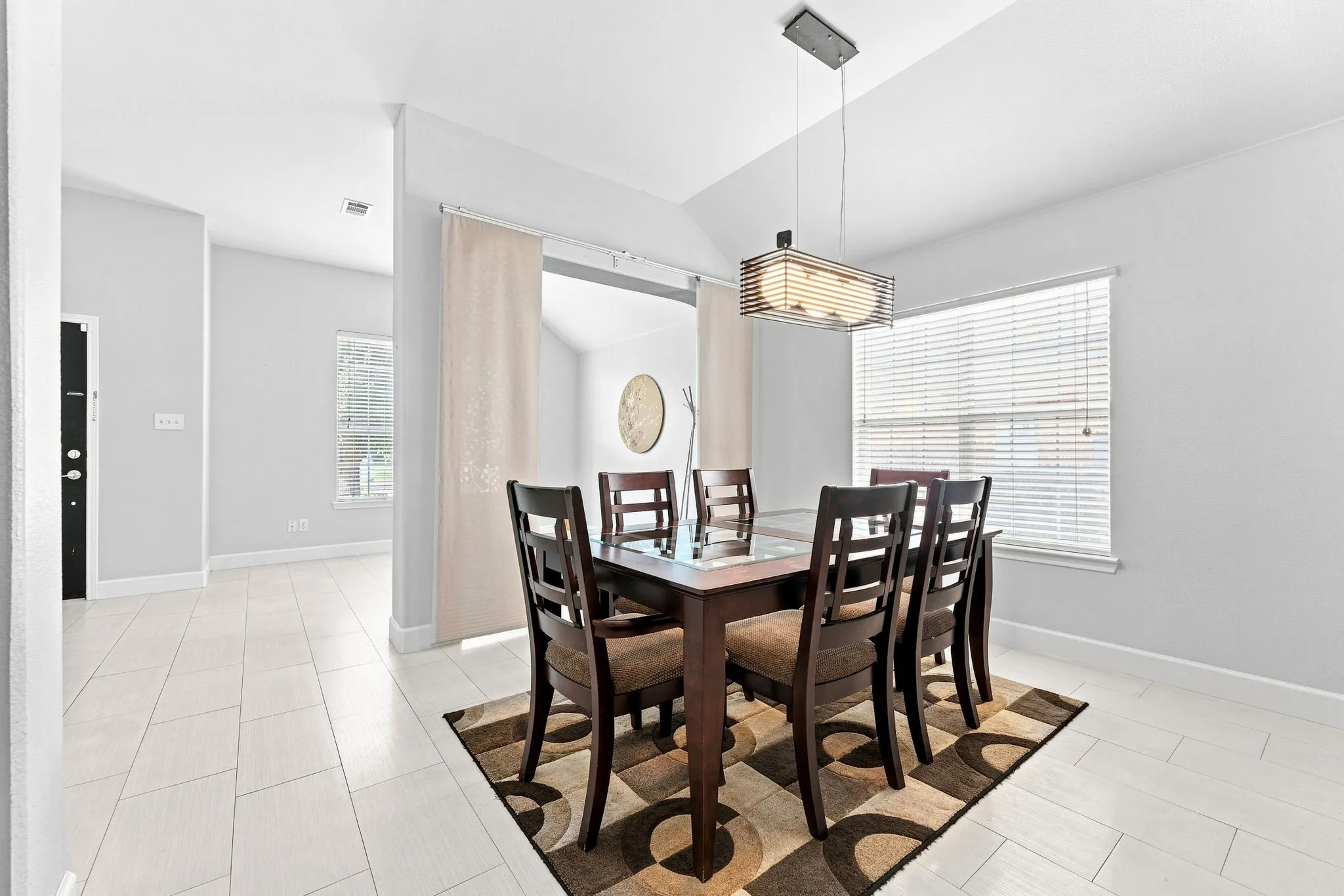 Elegant dining space anchored by a wood-finish table with seating for six, illuminated by a pendant light fixture
