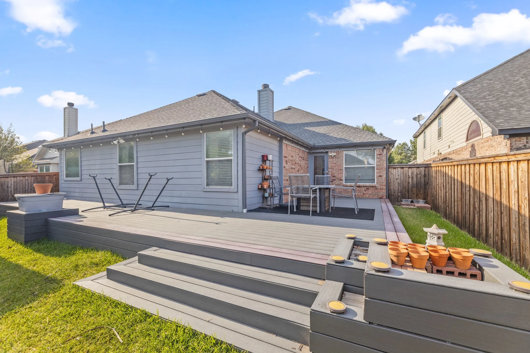 Expansive composite deck with multi-level gray composite decking and integrated planter boxes, overlooking a manicured lawn with mature landscaping