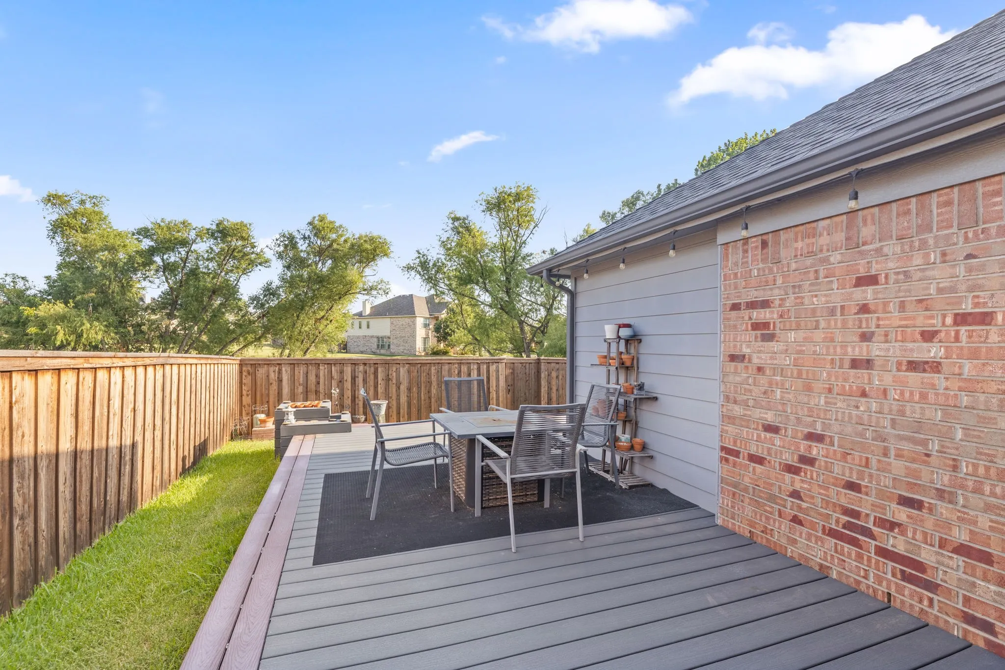 Spacious composite deck with gray wood-finish decking and black metal railing, anchoring an outdoor entertaining area with integrated dining space