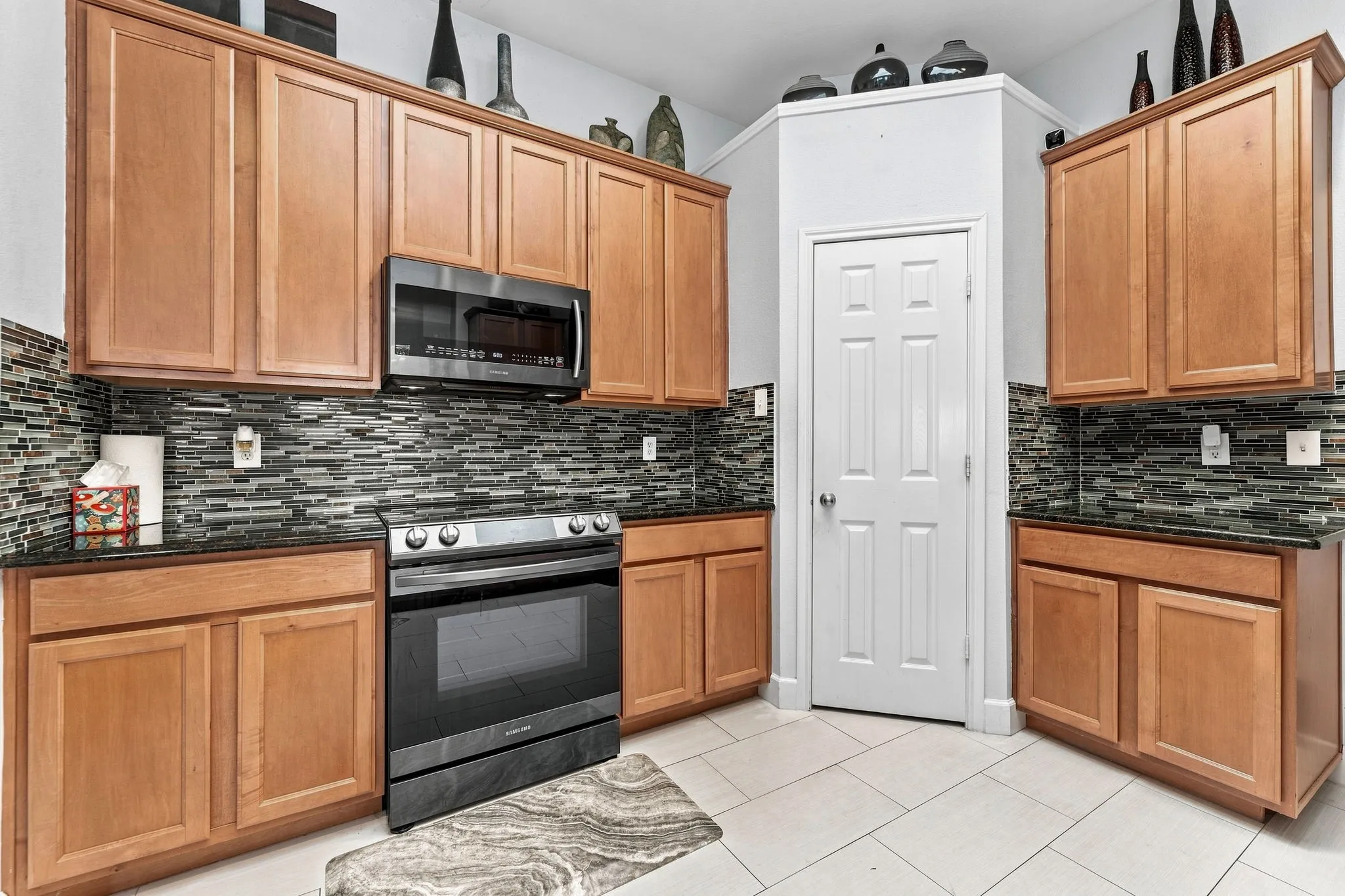 Warm wood cabinetry and stainless steel & black appliances define this galley-style kitchen, featuring a gas range, microwave, and ample storage throughout