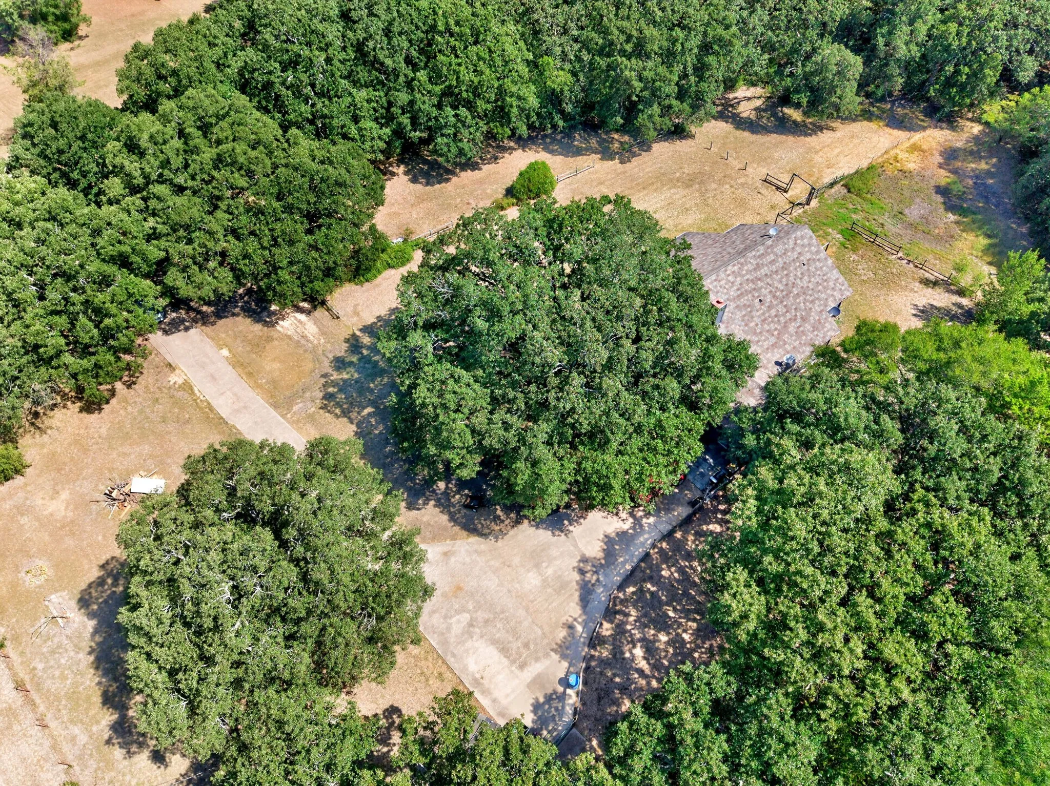 Aerial view of expansive wooded property featuring mature tree coverage, natural water features including a creek with rocky bed, and cleared land parcels suitable for development or preservation