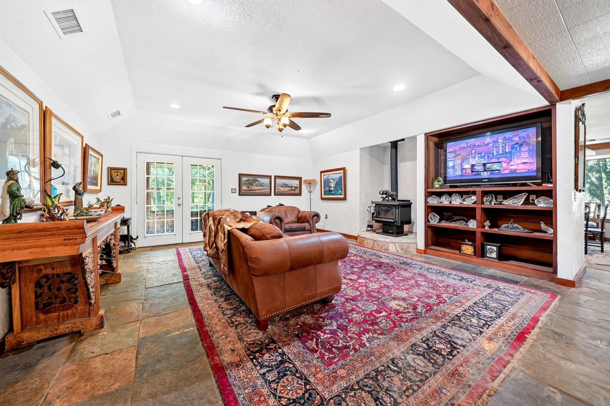 Spacious family room featuring hardwood flooring, a ceiling fan with integrated lighting, and built-in entertainment cabinetry with shelving