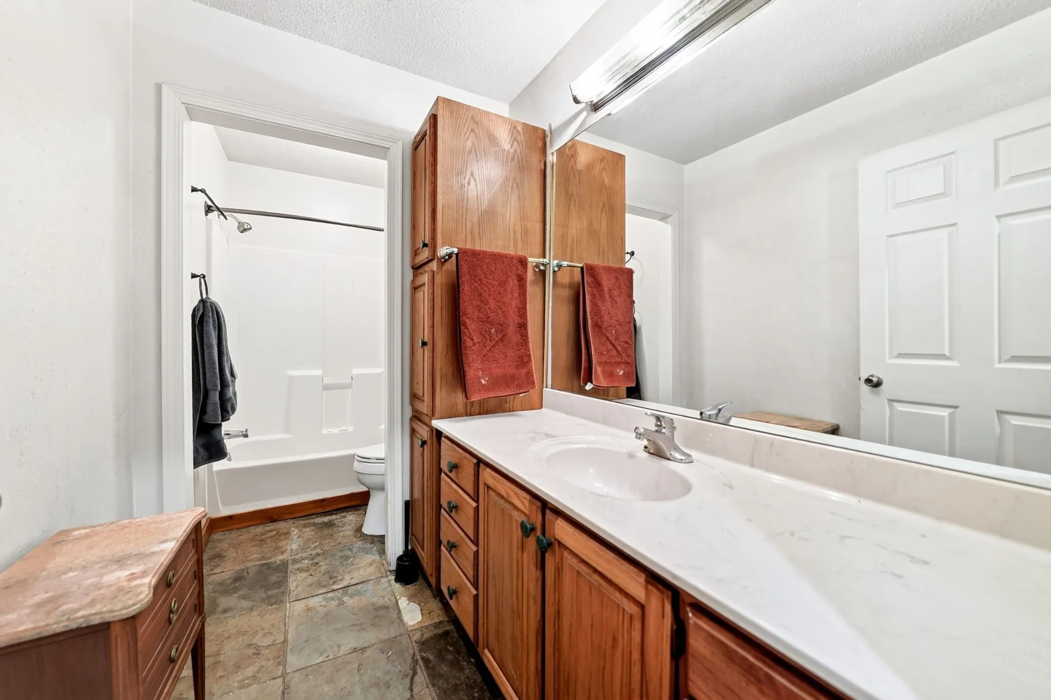 Spa-inspired master bathroom featuring dual vanities with wood cabinetry, marble countertops, and an expansive mirror