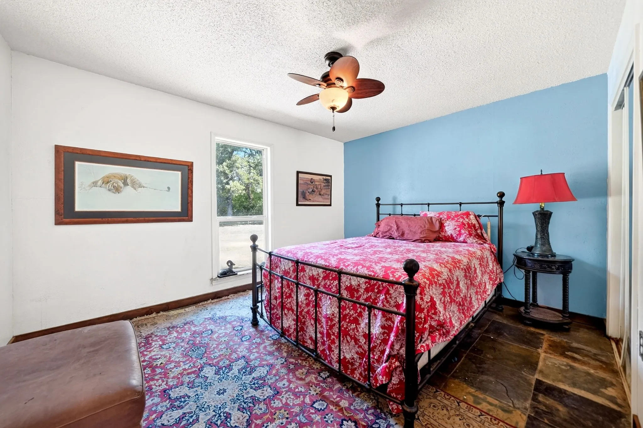 Charming bedroom featuring a decorative wrought-iron bed frame, wood-finish flooring, and two-tone wall treatment with soft blue accent wall