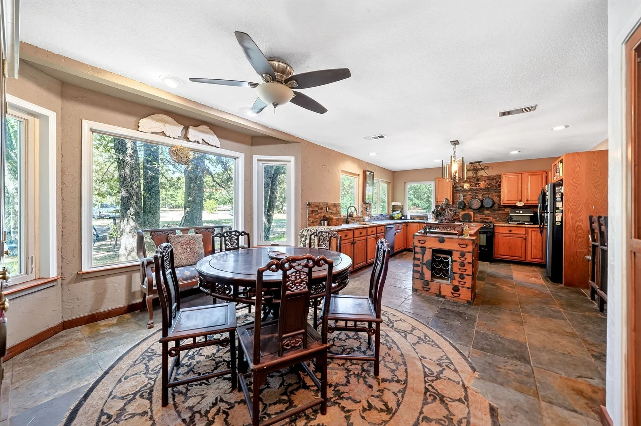 Open-concept kitchen and dining area featuring tile flooring, wood cabinetry, and a central island