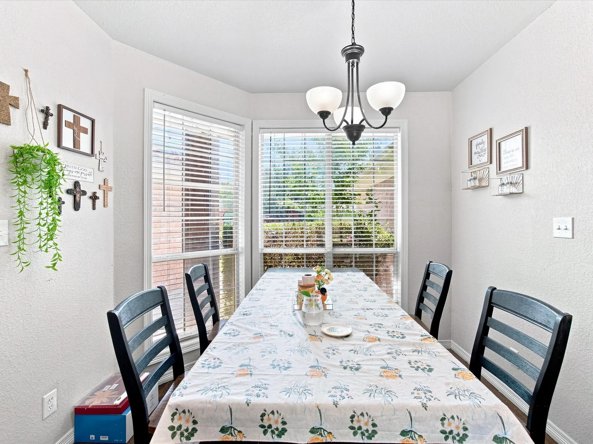 Bright dining area featuring expansive glass doors and windows with plantation shutters, a modern chandelier with opalescent shades, and hardwood-finish flooring