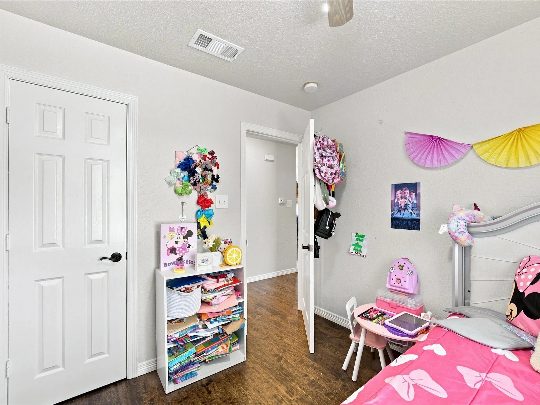 Wood-finish flooring, white paneled door, and textured ceiling