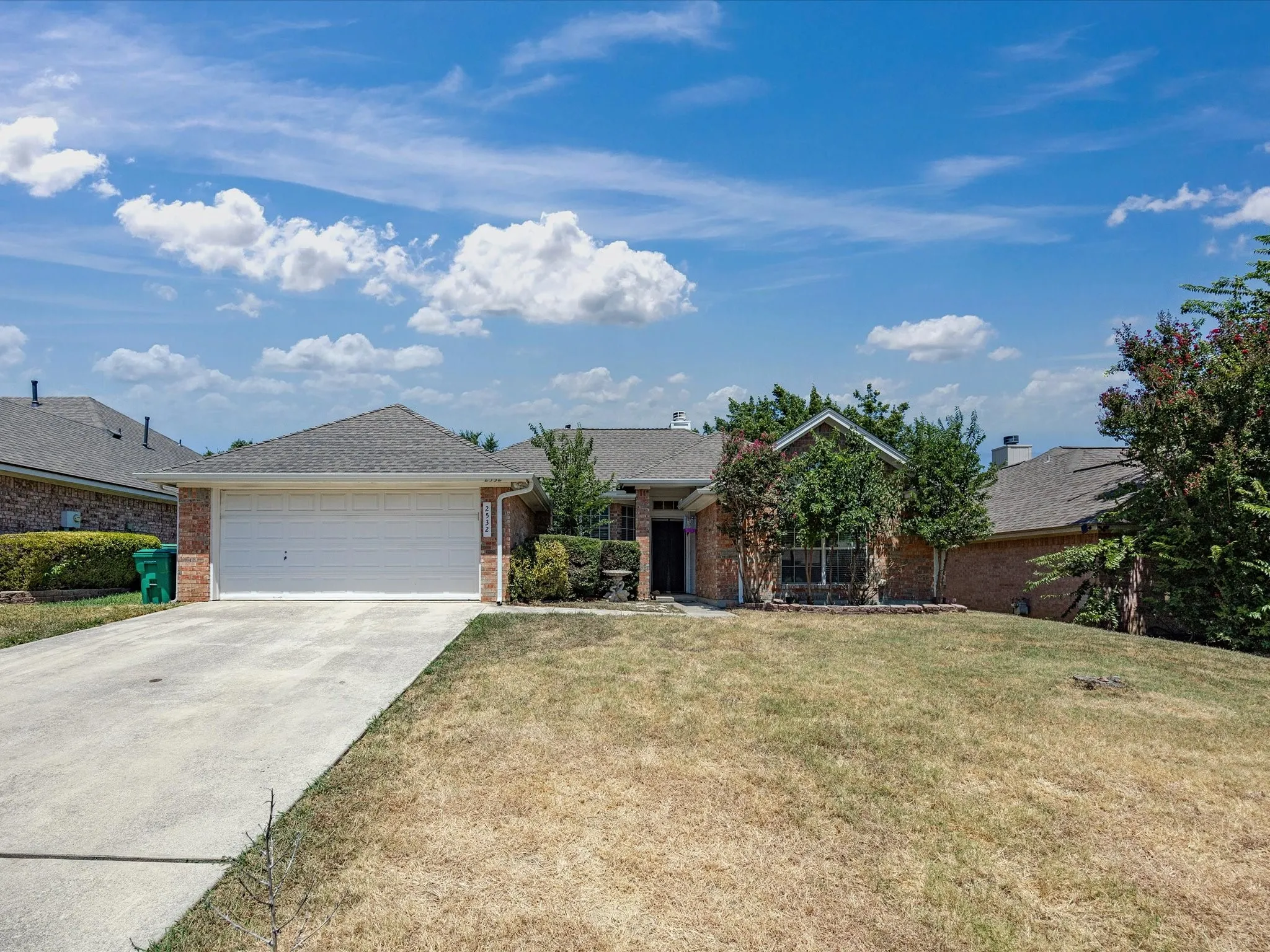 Welcoming single-story brick residence with a two-car garage, gabled roofline, and front-facing landscaping