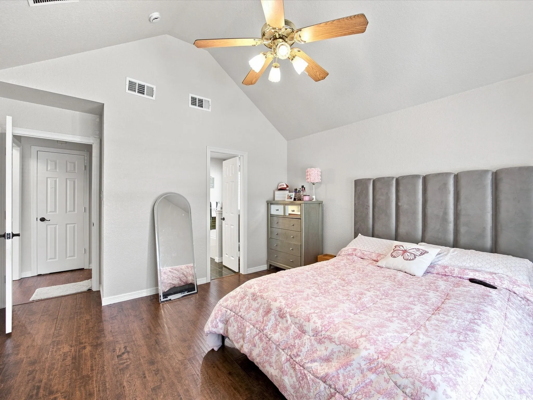 Vaulted ceiling with a ceiling fan, wood-finish flooring, and white interior doors