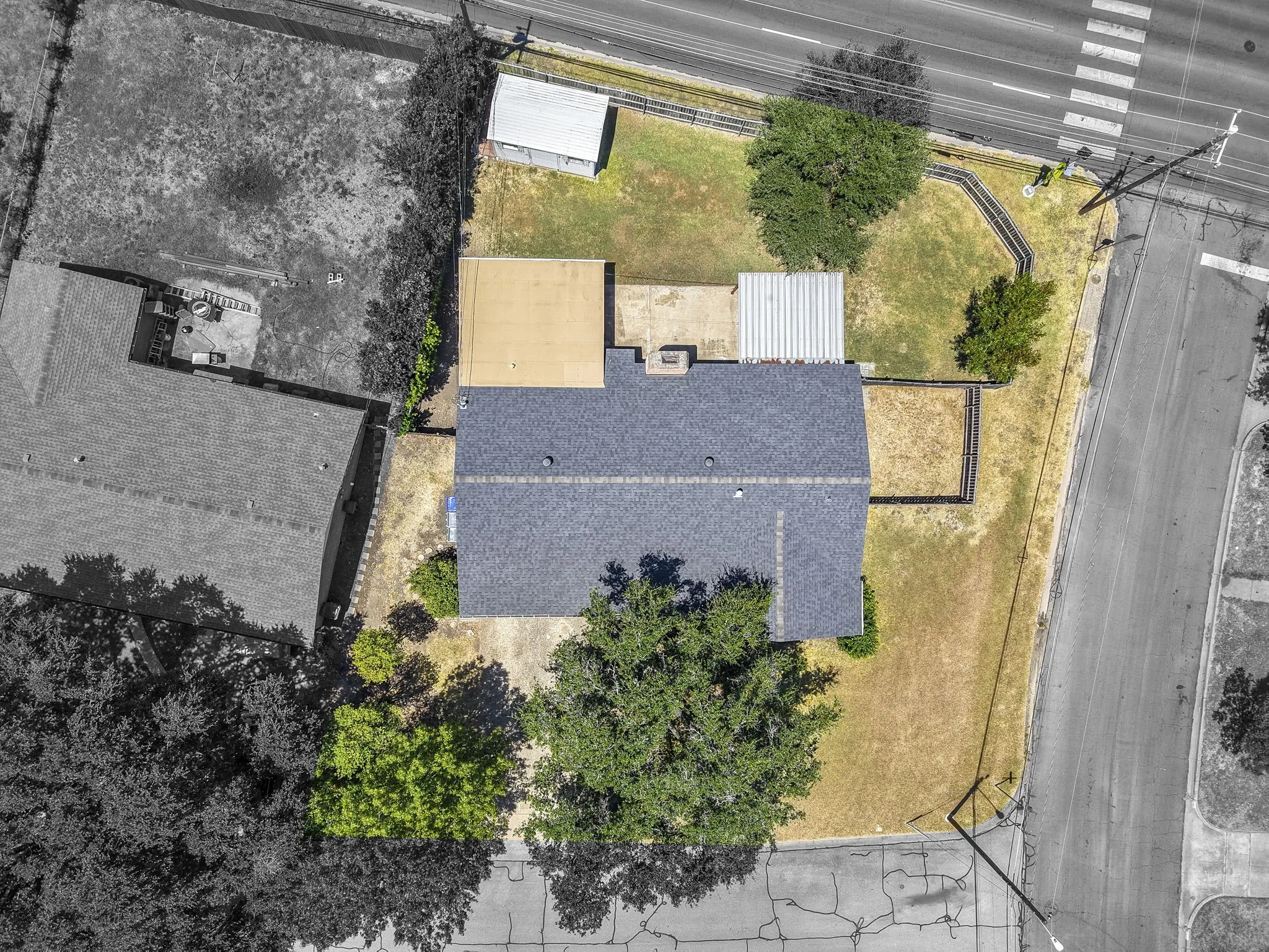 Pitched roof residence featuring an attached carport and a separate detached shed