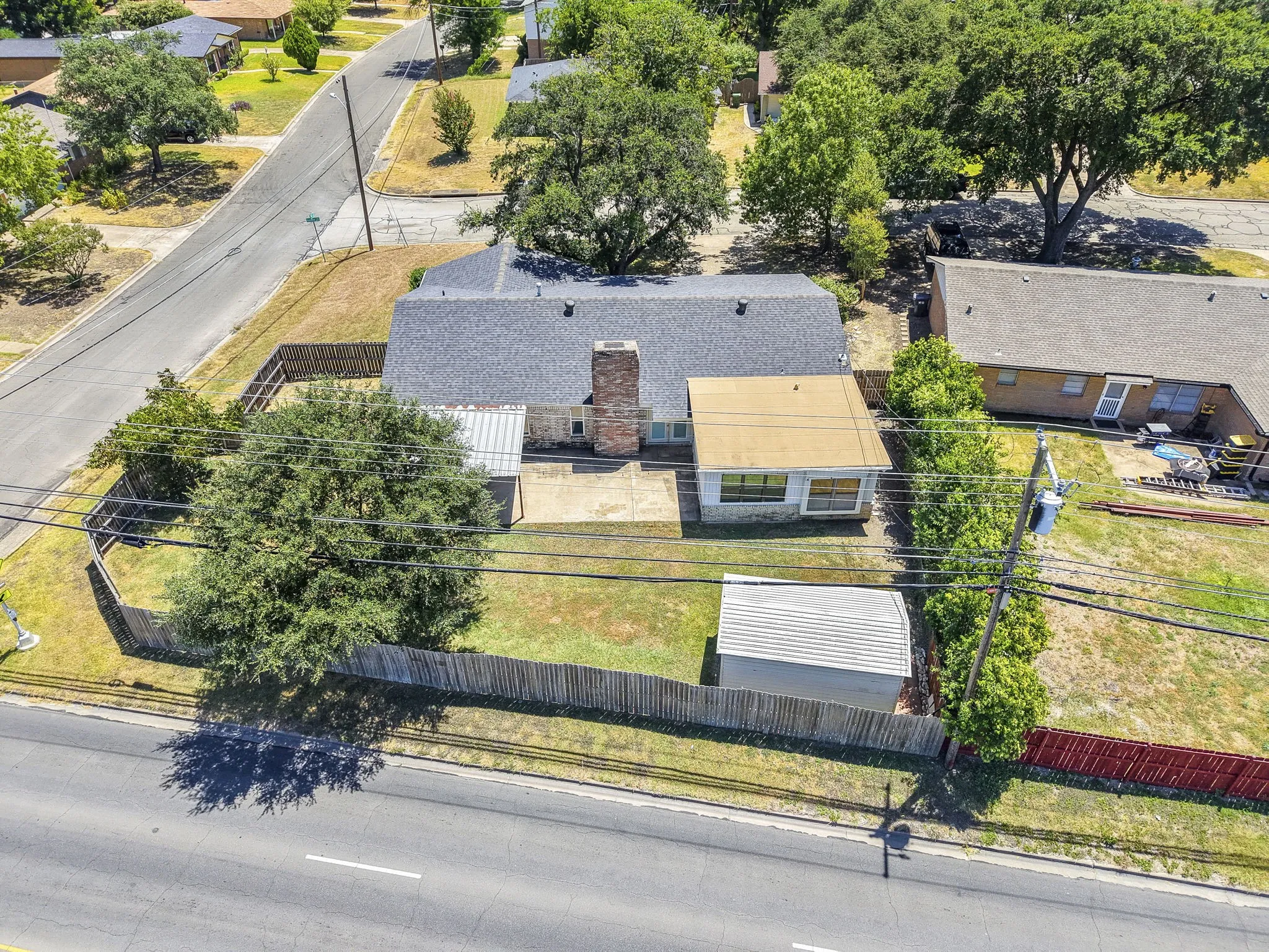 Fenced backyard with a storage shed, concrete patio, and mature trees