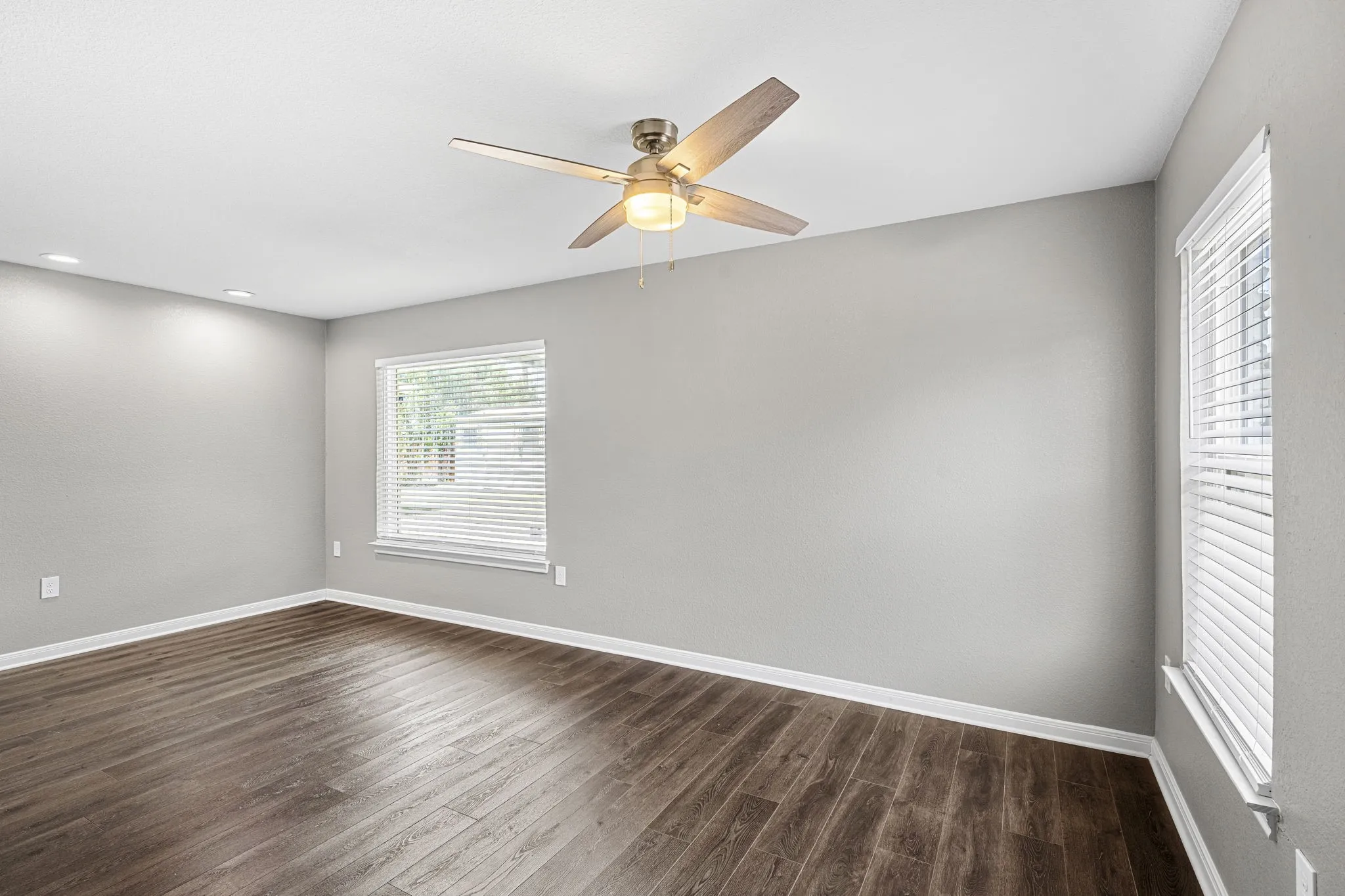 Wood-finish flooring, light grey walls, white trim, recessed lighting, and a ceiling fan