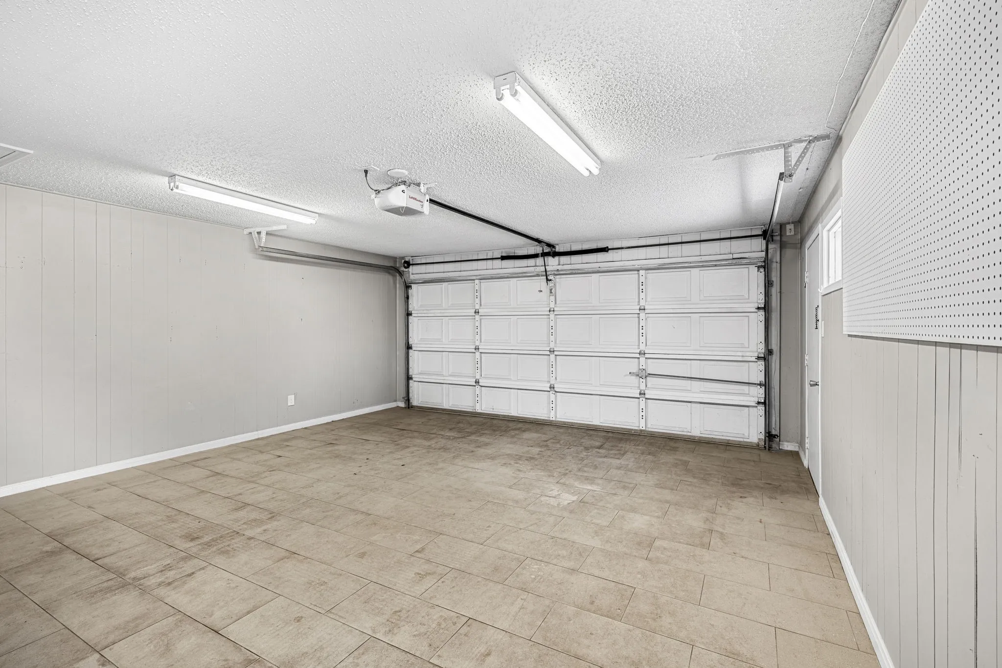 Garage featuring a sectional overhead door, automatic door opener, and tiled flooring