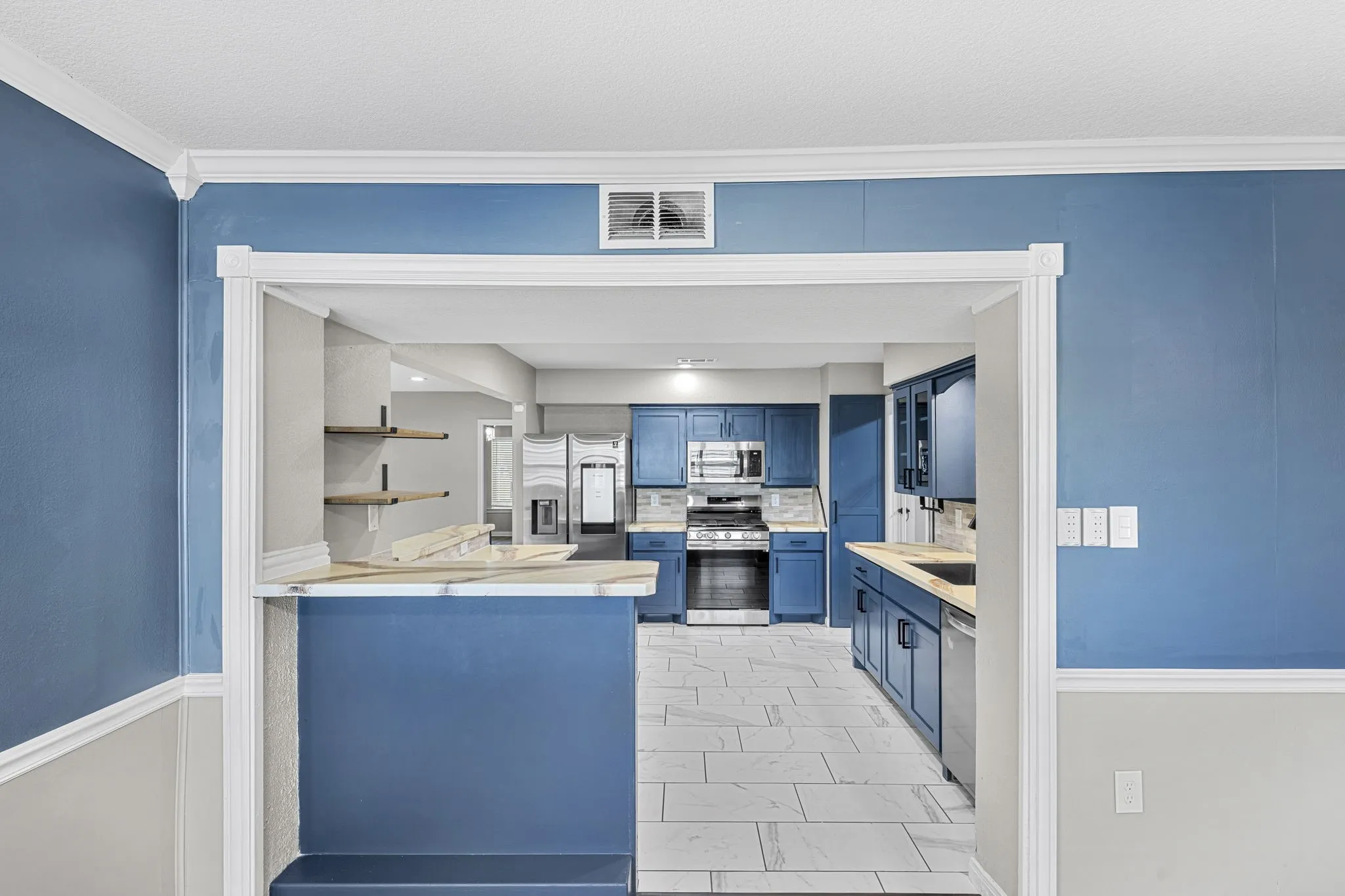 Kitchen featuring blue cabinetry, stainless steel appliances, and a tile floor