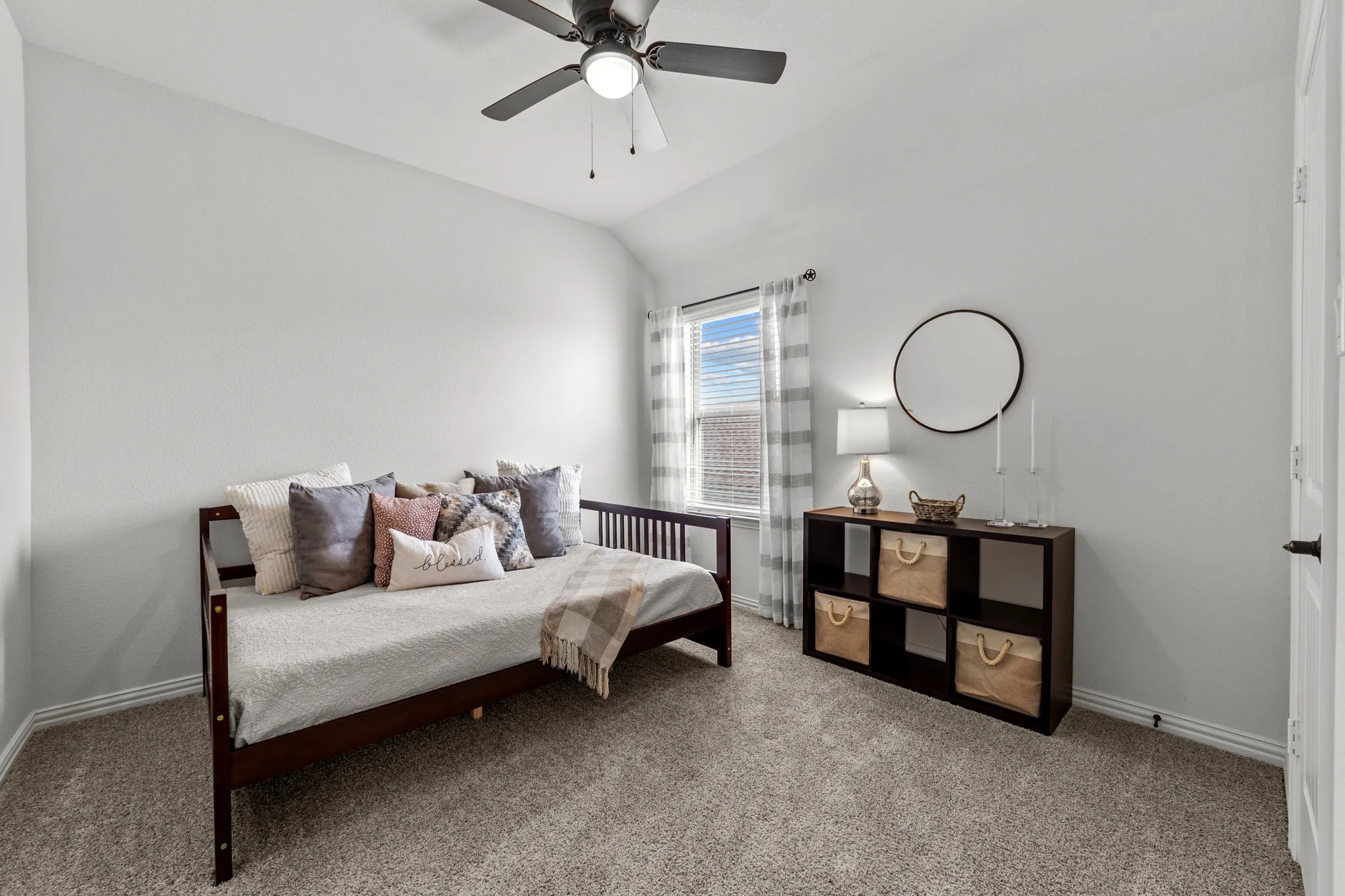 Bright secondary bedroom featuring neutral carpet flooring, ceiling fan with integrated lighting, large window.