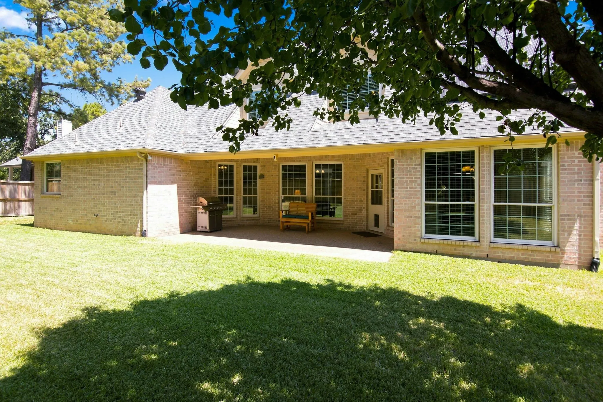 Expansive backyard featuring a brick exterior and a covered patio