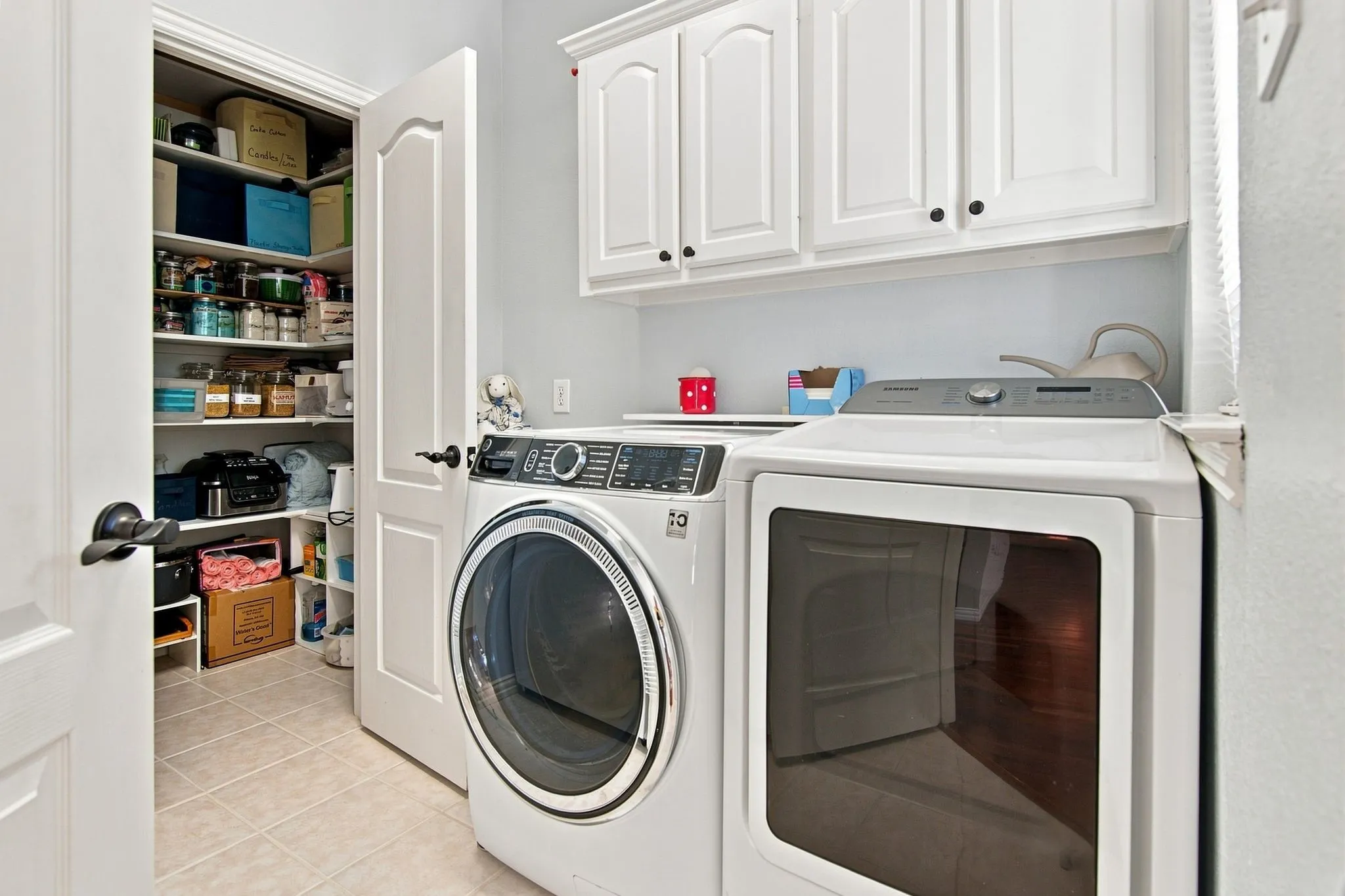 Laundry area with white cabinetry, tile flooring, and a walk-in pantry