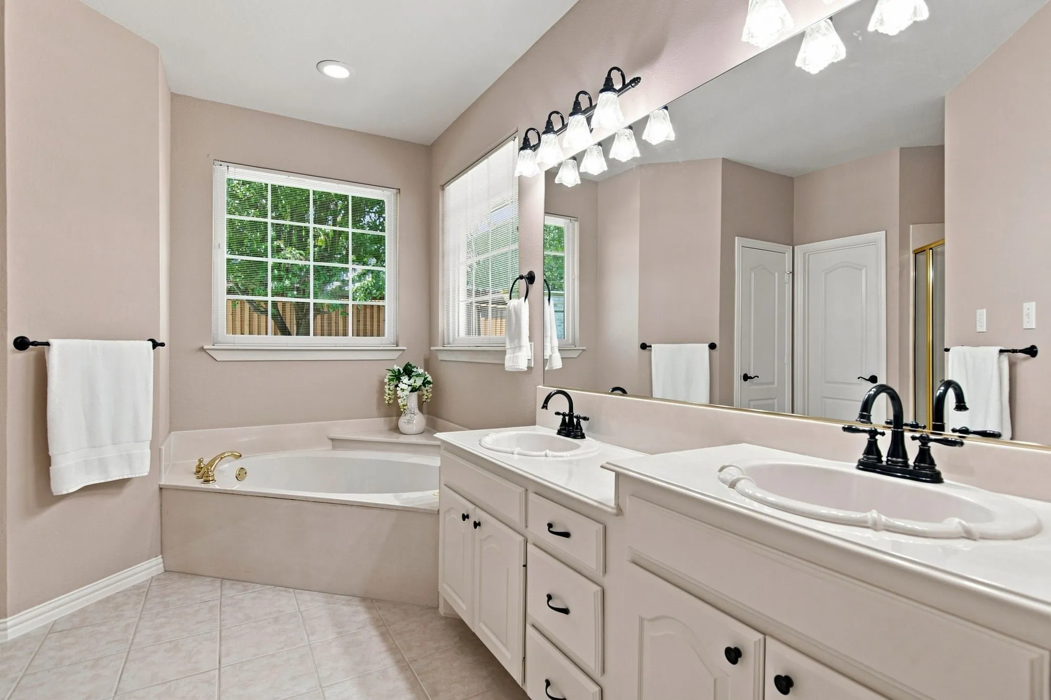 Dual vanity with undermount sinks, built-in soaking tub, and large framed window