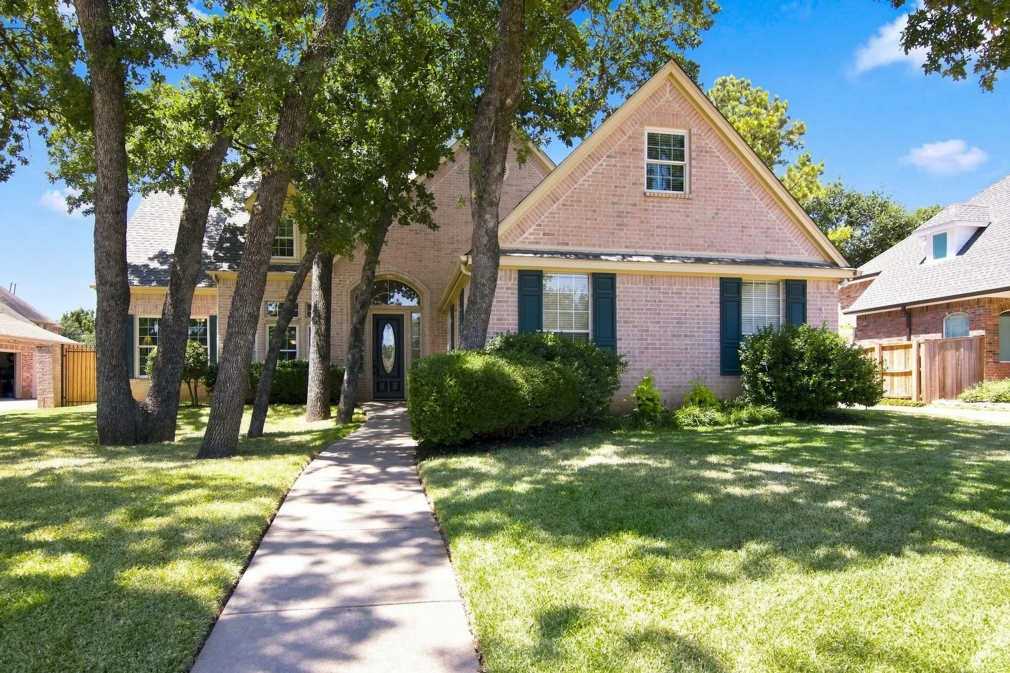 Charming brick residence featuring a gabled roofline with dormer window, black shutters, and a welcoming front entrance