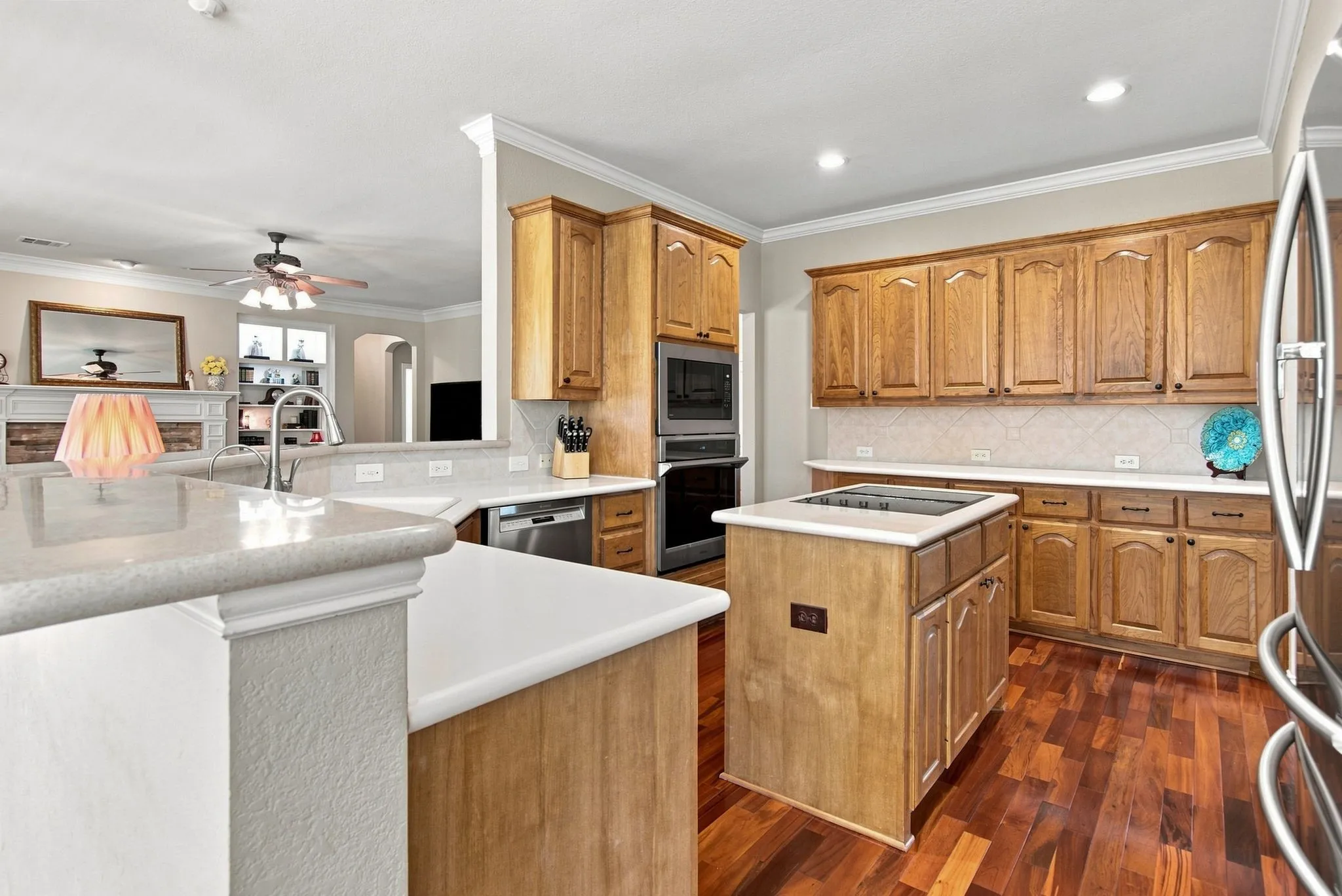 Chef's kitchen featuring custom wood cabinetry, dual islands with white quartz countertops, stainless steel appliances, recessed lighting, and hardwood flooring throughout the space
