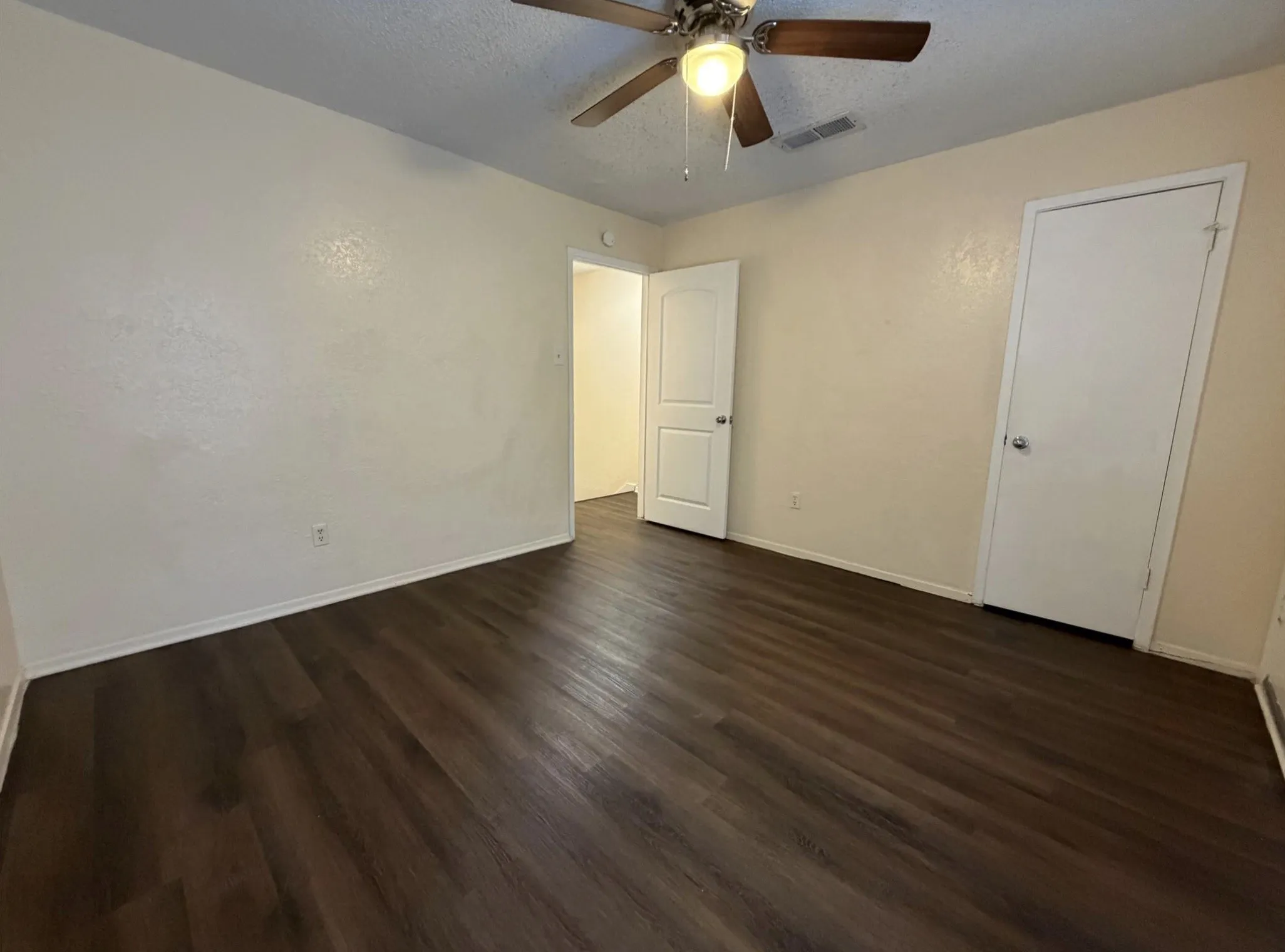 Wood-finish flooring, ceiling fan with integrated lighting, and neutral wall tones