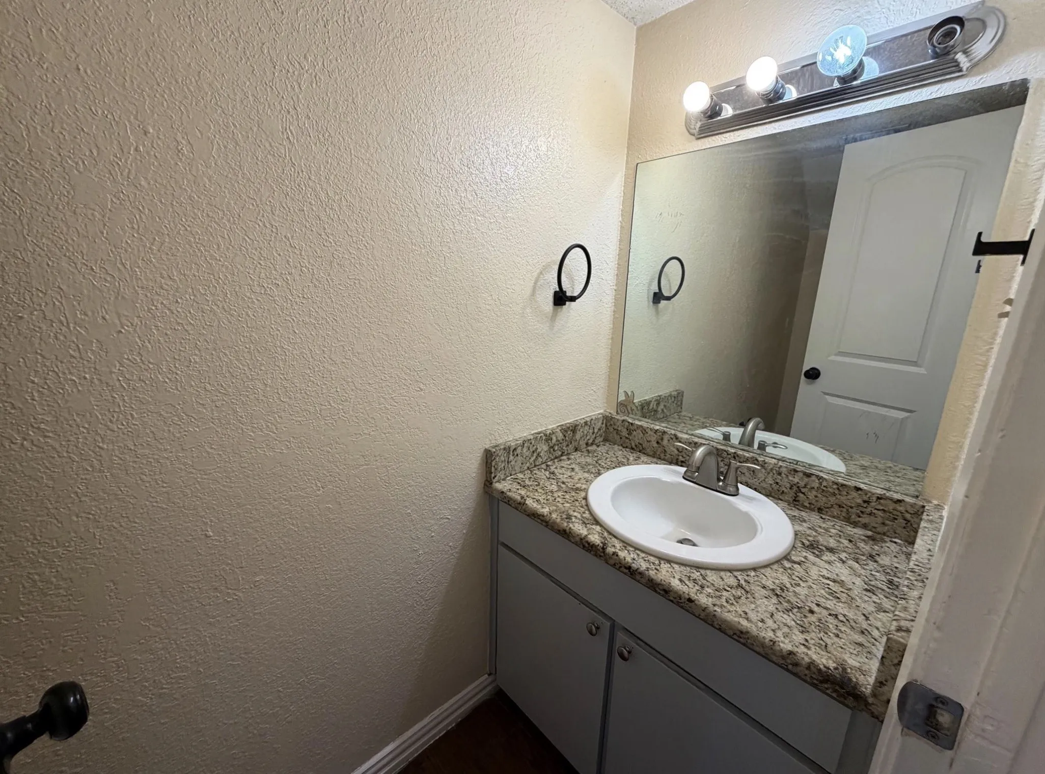 Vanity with a granite-style countertop, undermount sink, and brushed nickel faucet