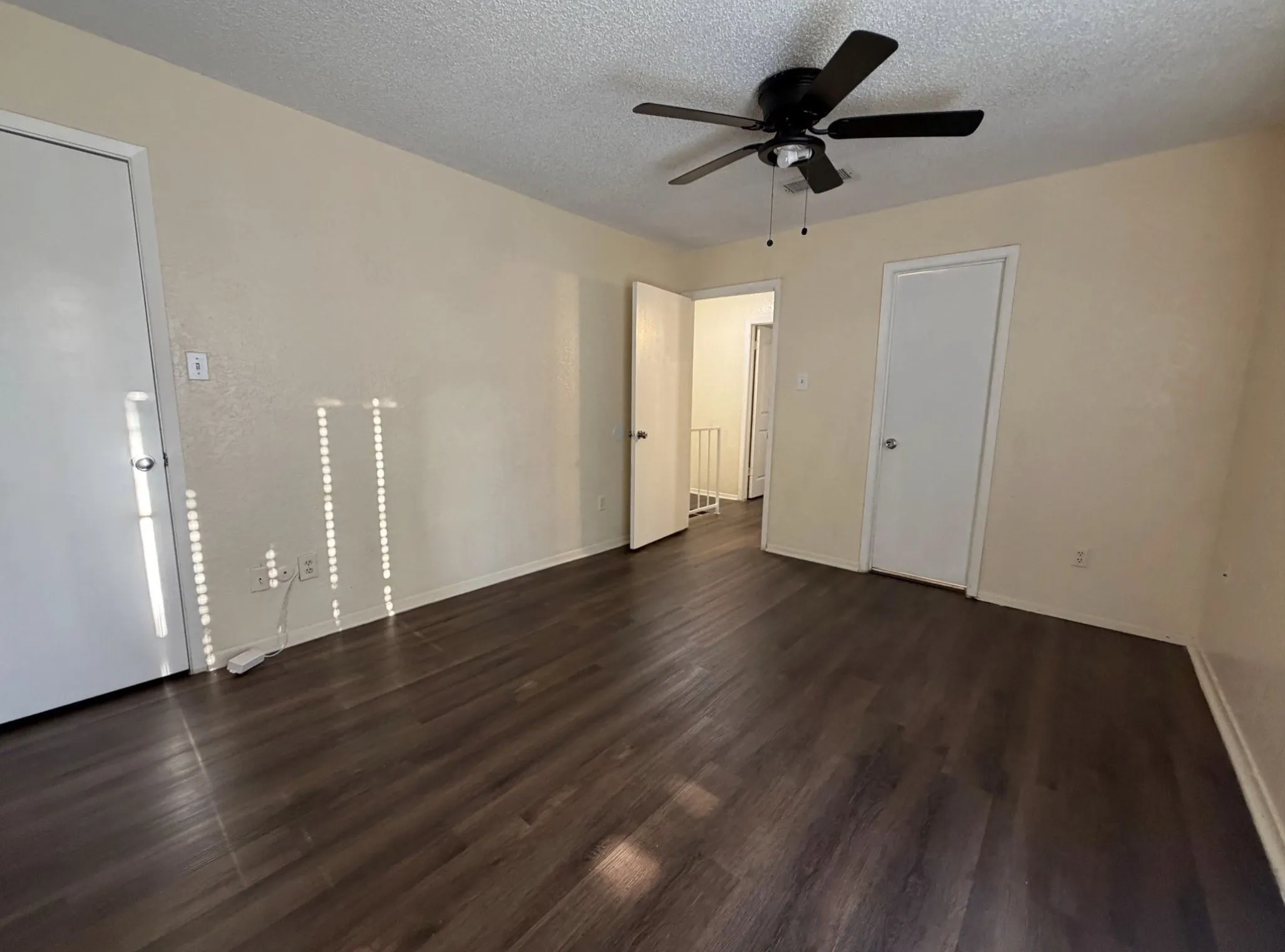 Wood-finish flooring, ceiling fan with light fixture, and neutral wall tones