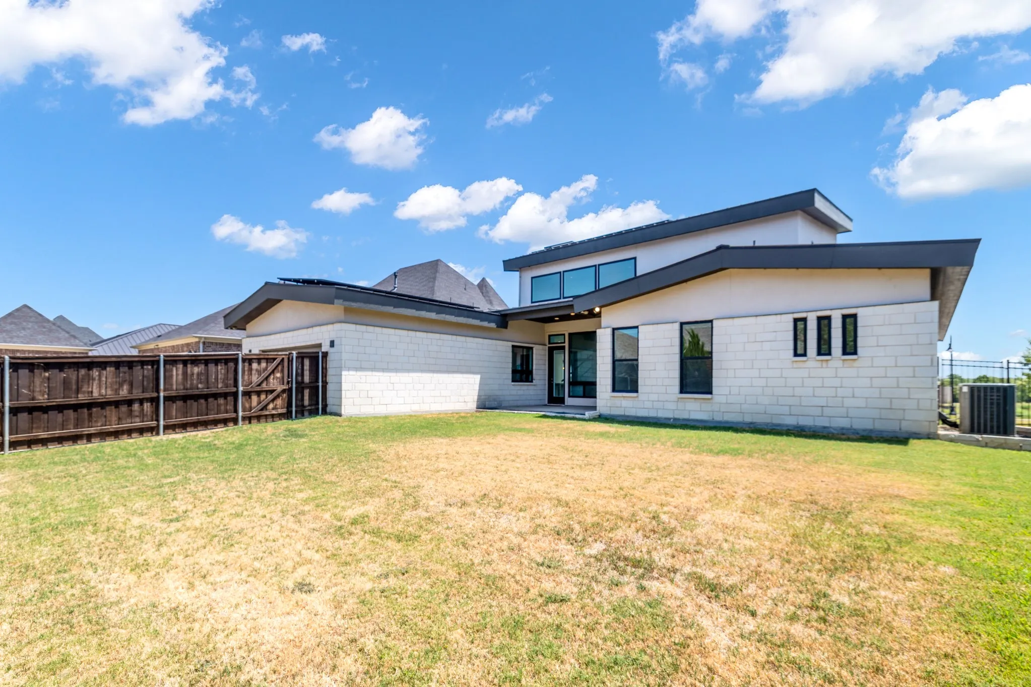 Modern residence featuring a clean-lined architectural design with a two-story profile, white exterior cladding, and dark roof accents