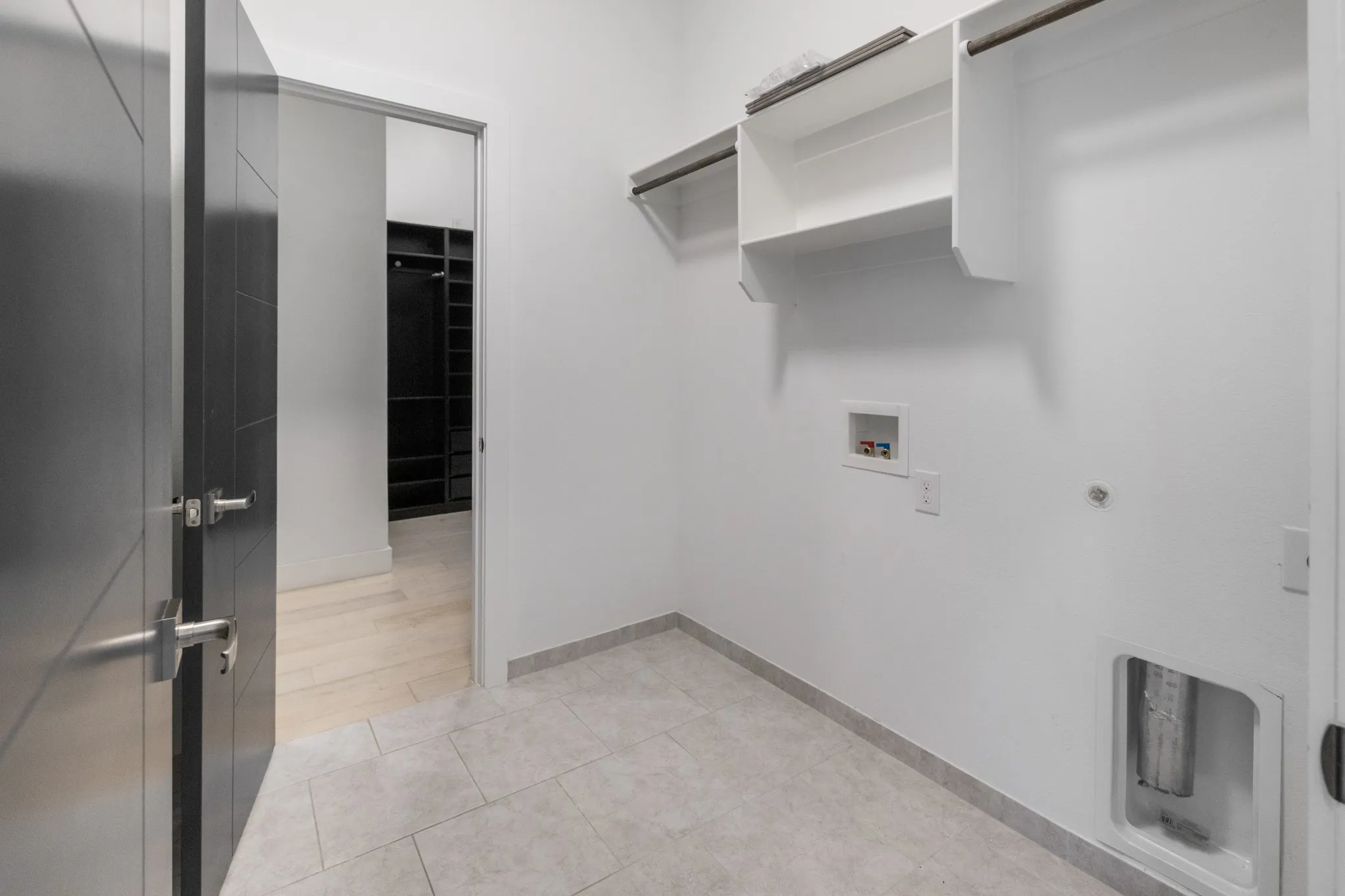 Modern utility space featuring polished concrete flooring, white walls, and open shelving with metal brackets