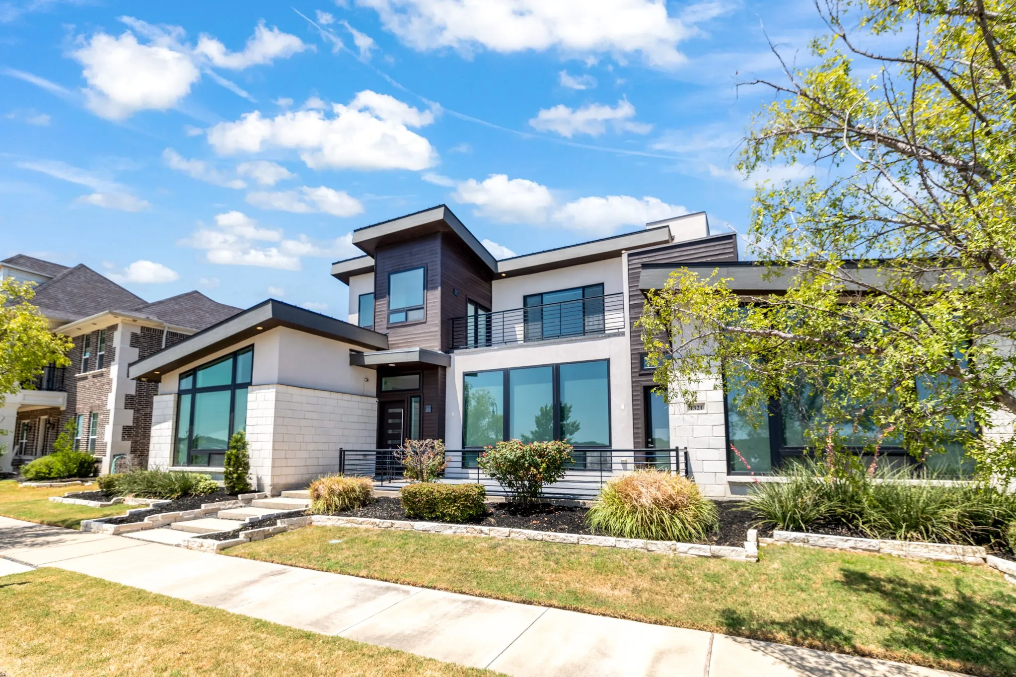 Modern two-story residence featuring a mixed-material exterior with dark metal accents, expansive multi-pane windows, and a clean horizontal roofline