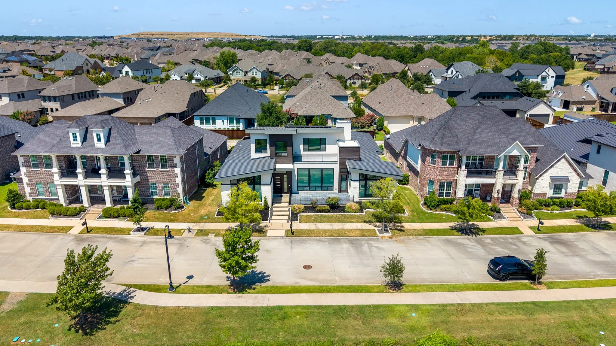 Striking contemporary residence showcasing a symmetrical facade with mixed exterior materials including brick and stone accents, expansive glass panels, and a flat roofline