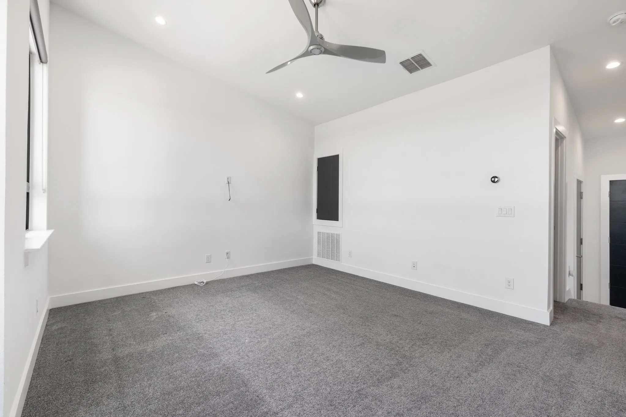 Spacious room with fresh white walls, neutral carpet flooring, and recessed ceiling lighting