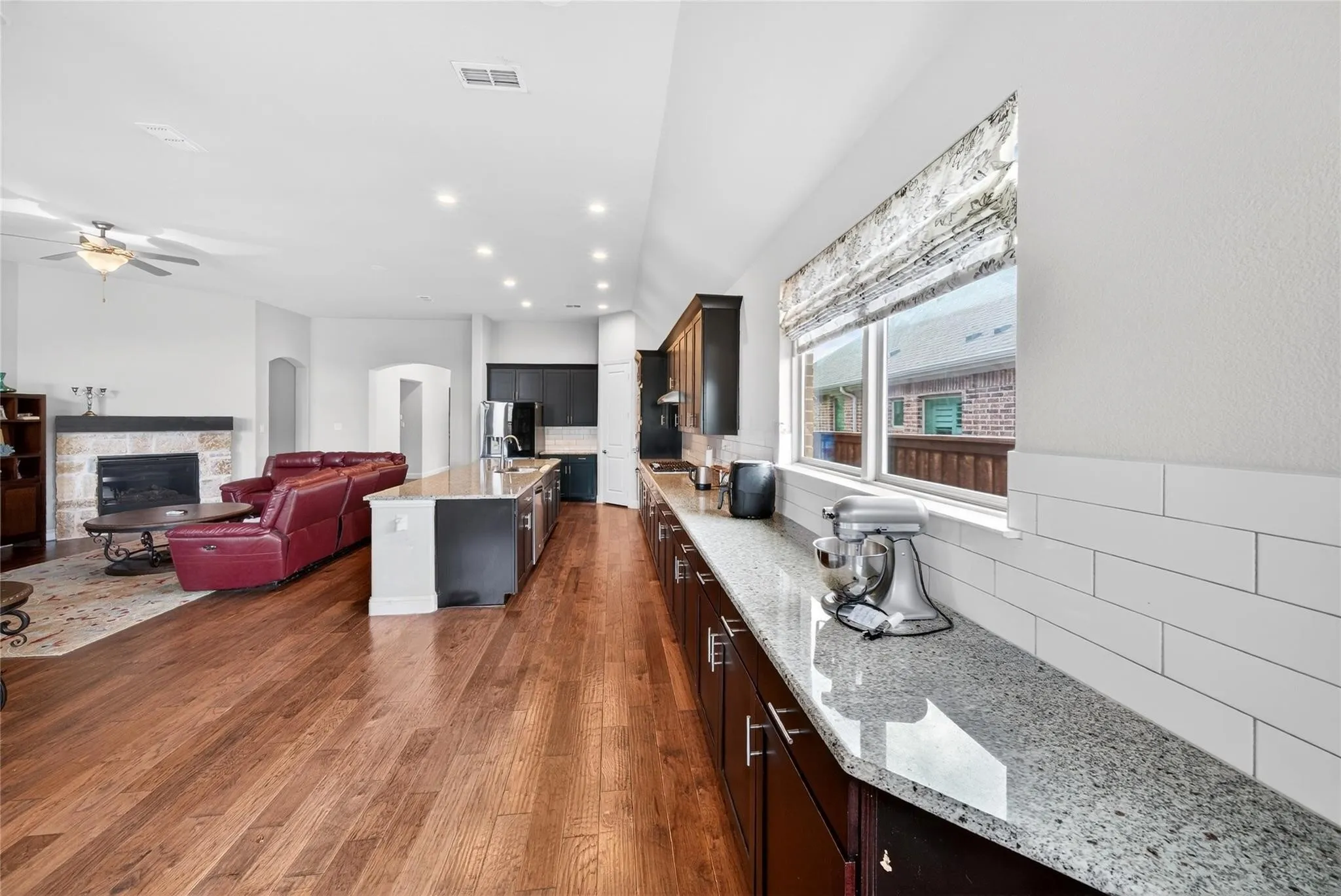Hardwood flooring throughout, kitchen with granite countertops, white subway tile backsplash, and dark wood cabinetry