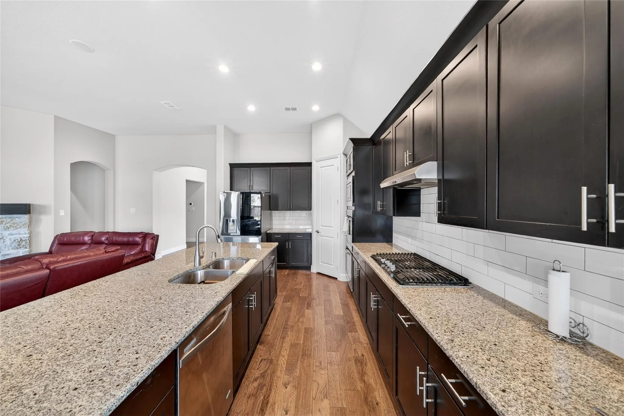 Spacious kitchen featuring an extended island, dark wood-finish cabinetry, stainless steel appliances, and a gas cooktop