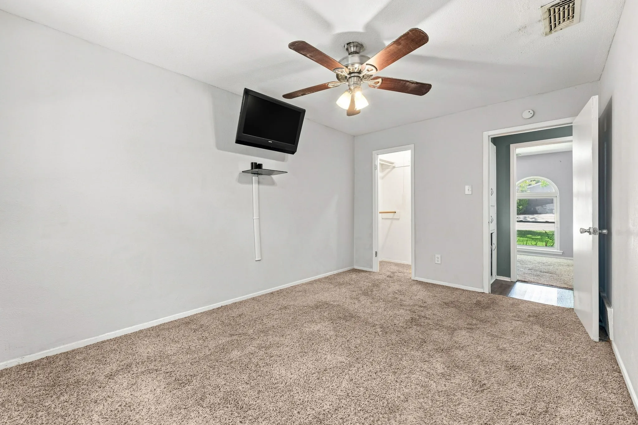 Carpeted room with a ceiling fan and light fixture