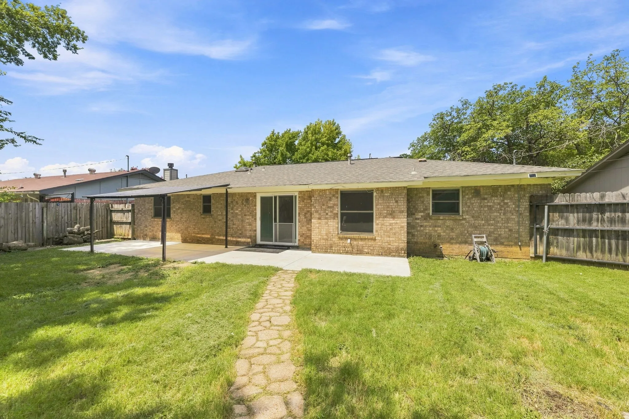 Brick ranch home with an expansive rear lawn featuring mature landscaping and established trees