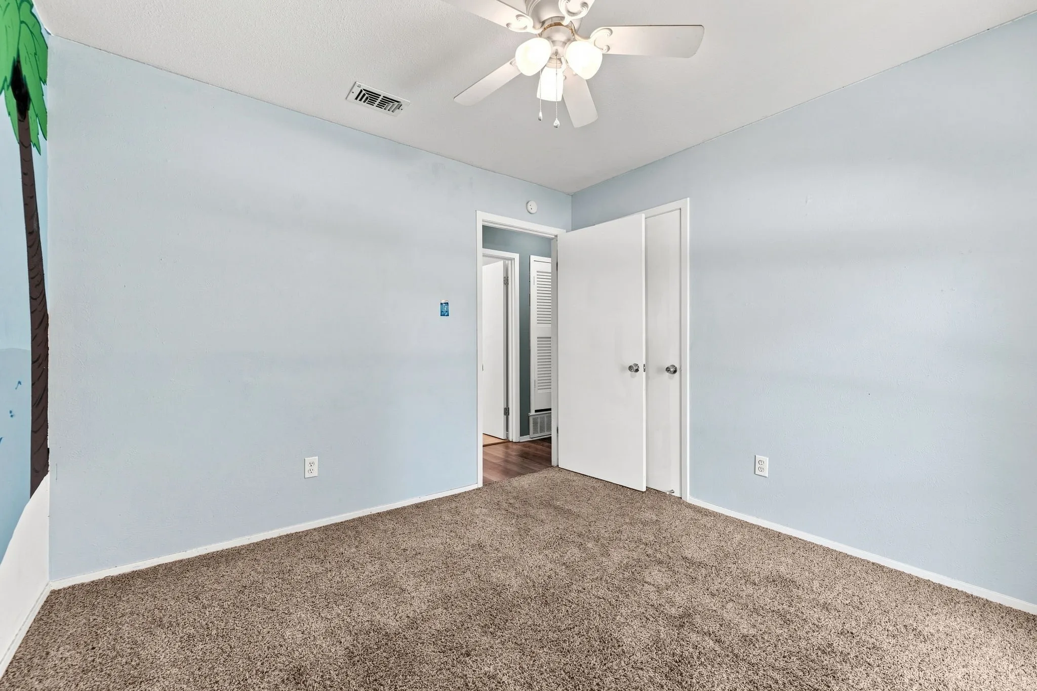Plush carpeting, ceiling fan with integrated lighting, and a double-door closet