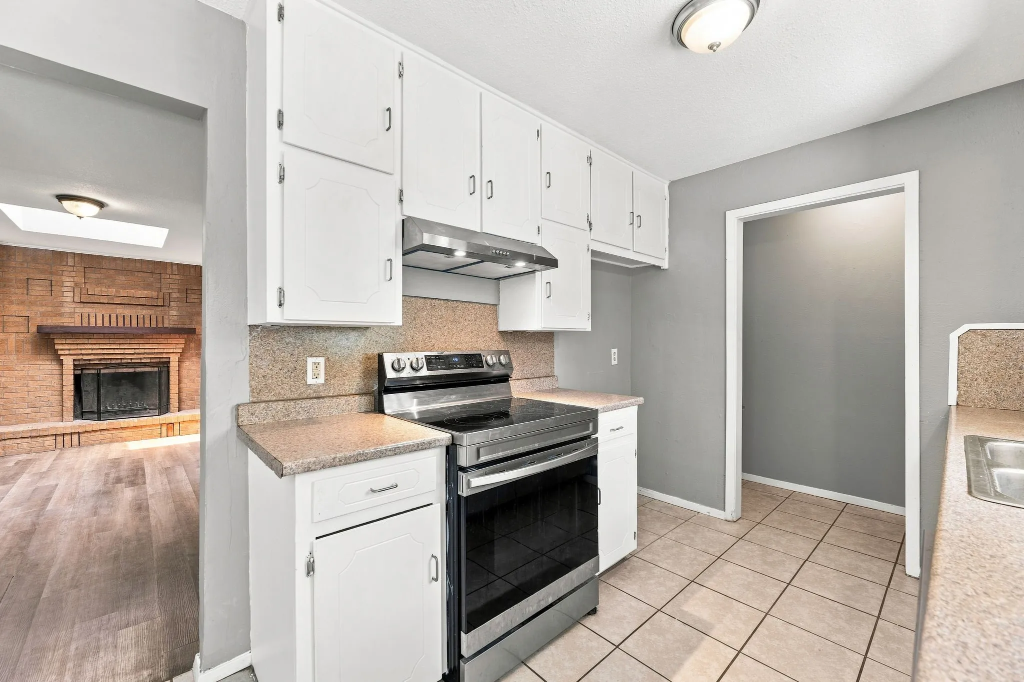 Bright kitchen featuring white cabinetry, stainless steel appliances, granite countertops, and tile flooring