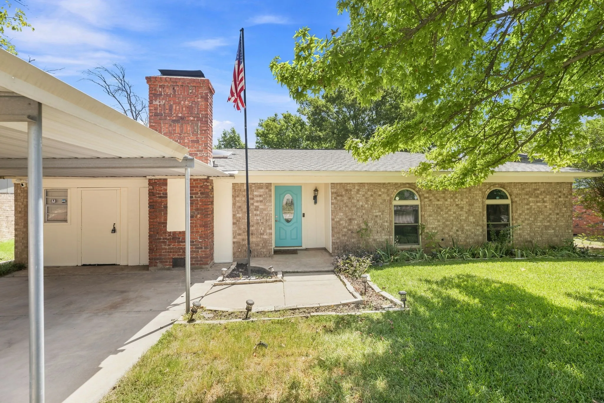 Welcoming brick and stone facade with turquoise entry door and arched transom windows