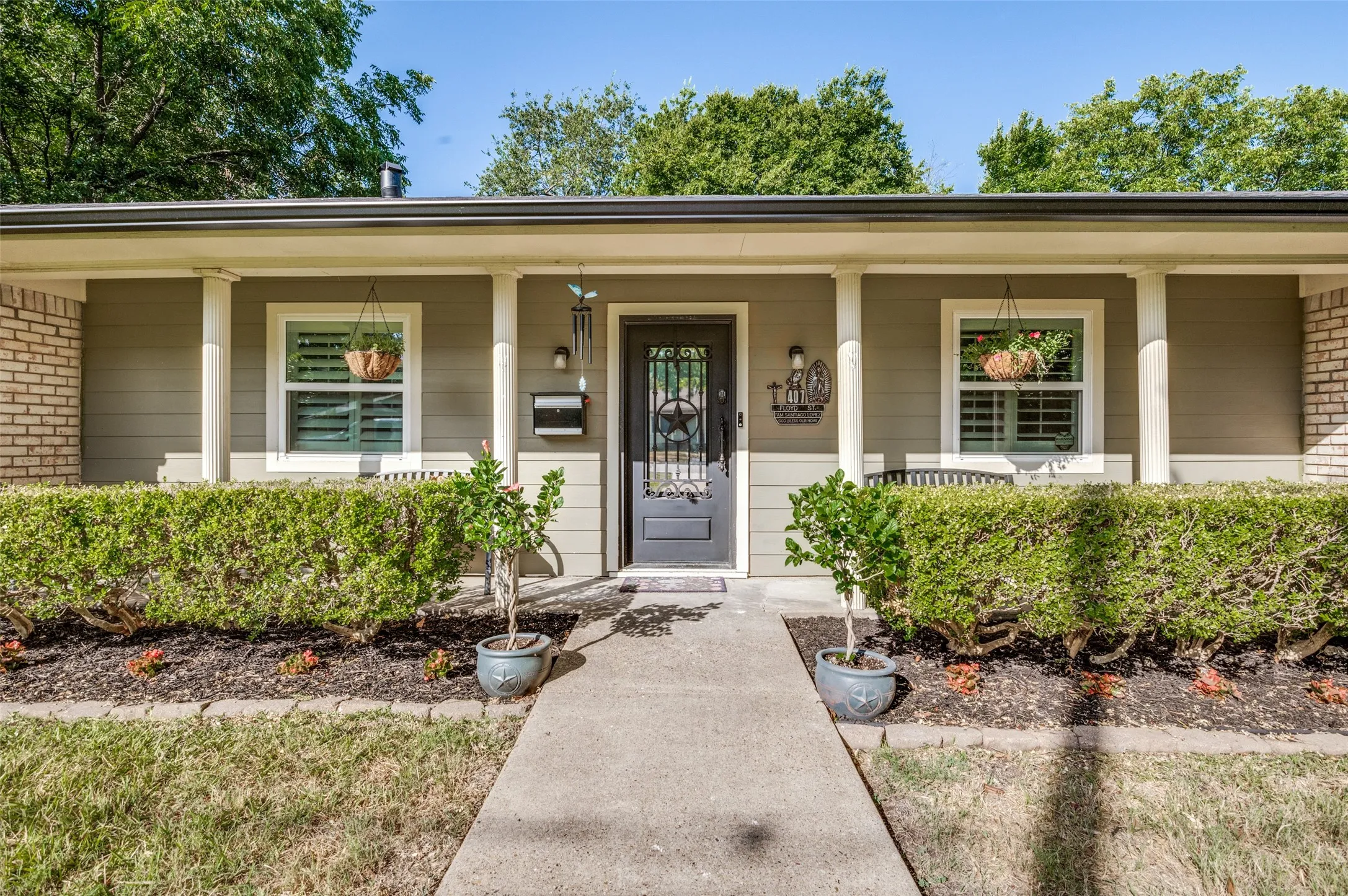 Charming brick front elevation featuring a covered front porch with white columns, recessed lighting, and dual windows flanking a centered entry door