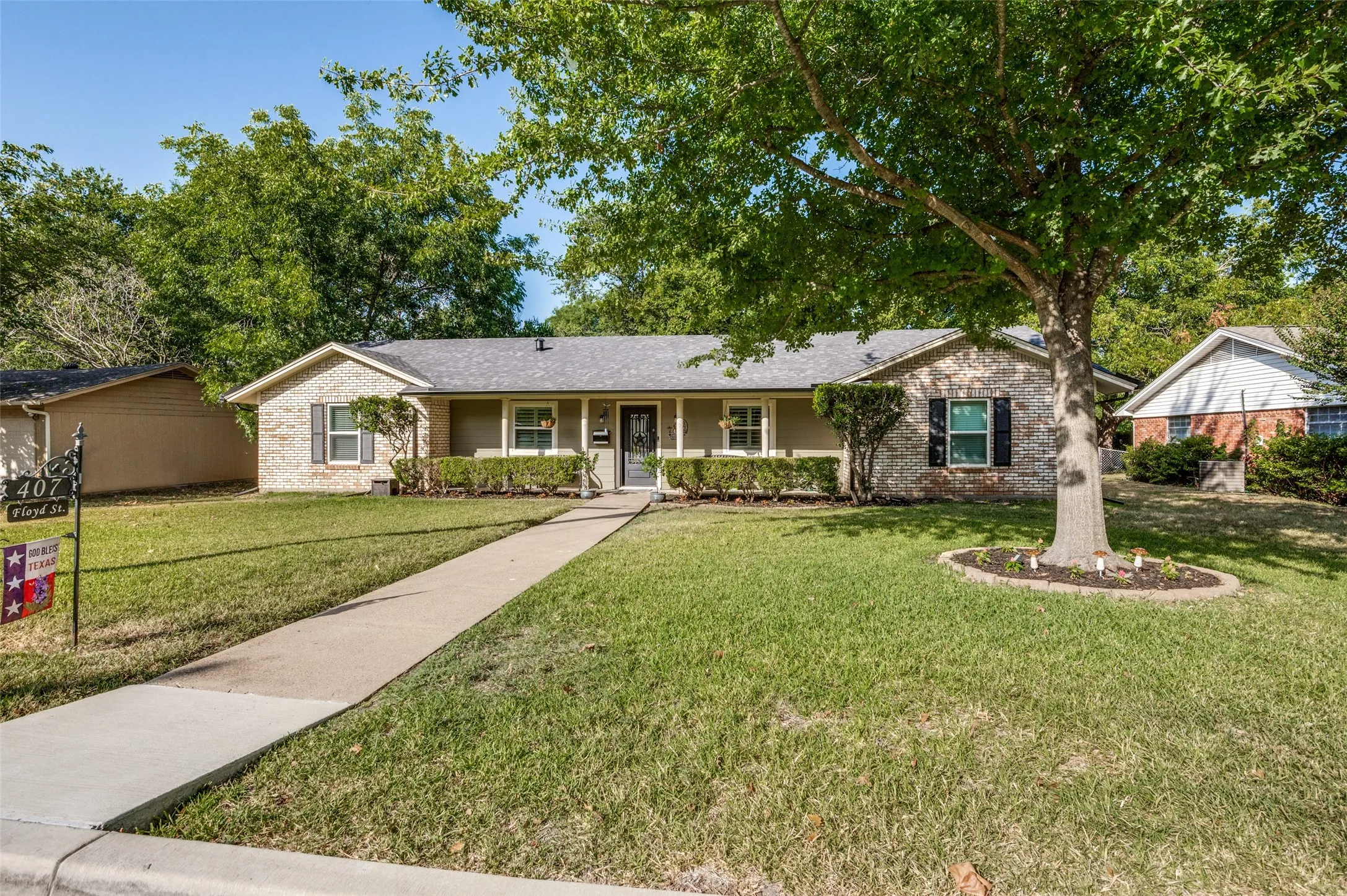 Charming single-story brick residence with a welcoming front porch, mature landscaping, and a manicured lawn