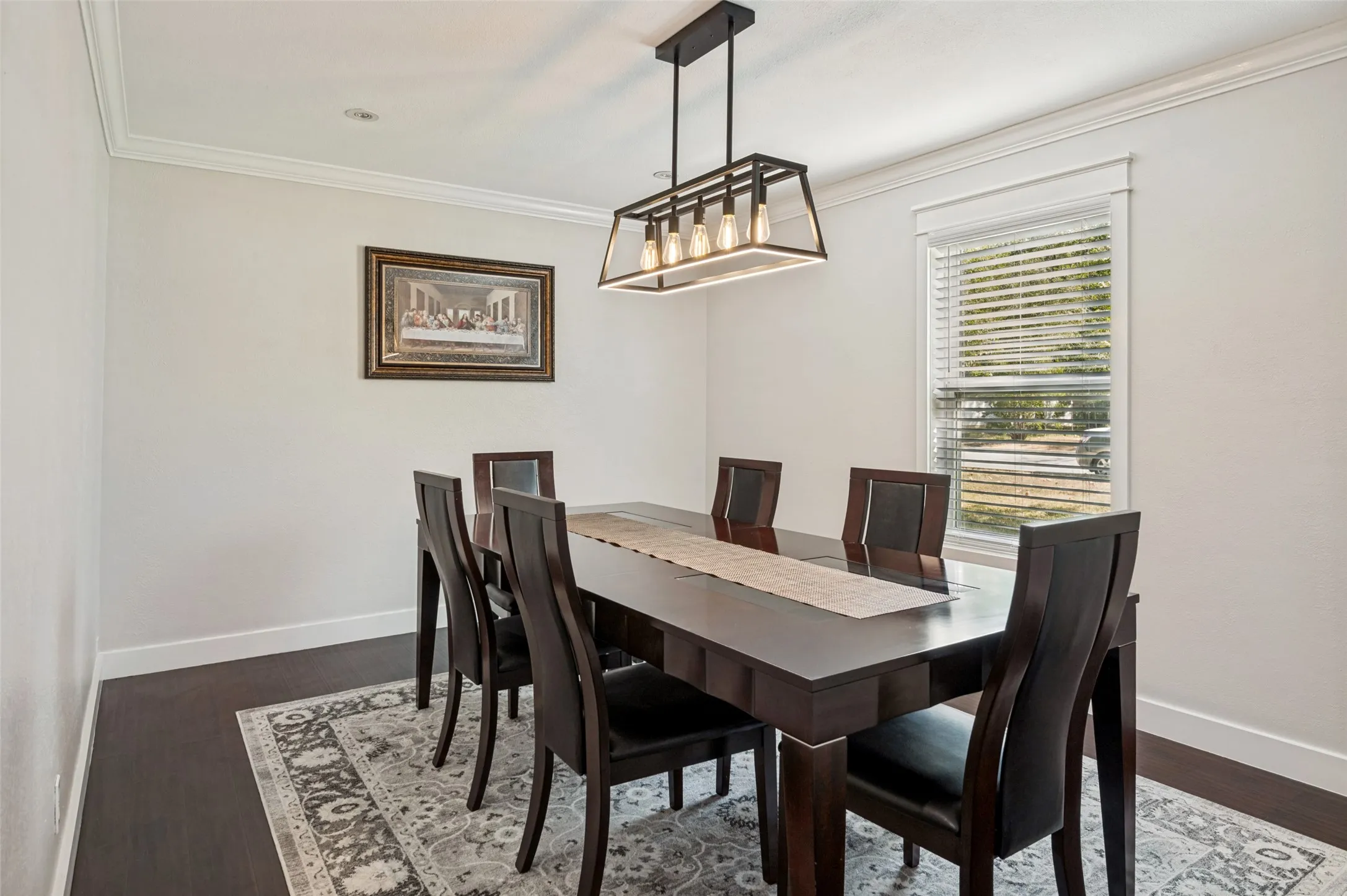 Elegant formal dining room showcasing a dark wood table with seating for six, dark wood chairs with upholstered backs, and wide-plank dark hardwood flooring