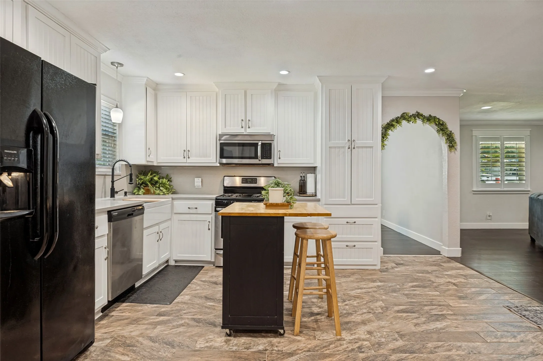 Chef's kitchen featuring white cabinetry with brushed nickel hardware, stainless steel appliances including a built-in microwave, and a center island with wood-finish countertop and seating